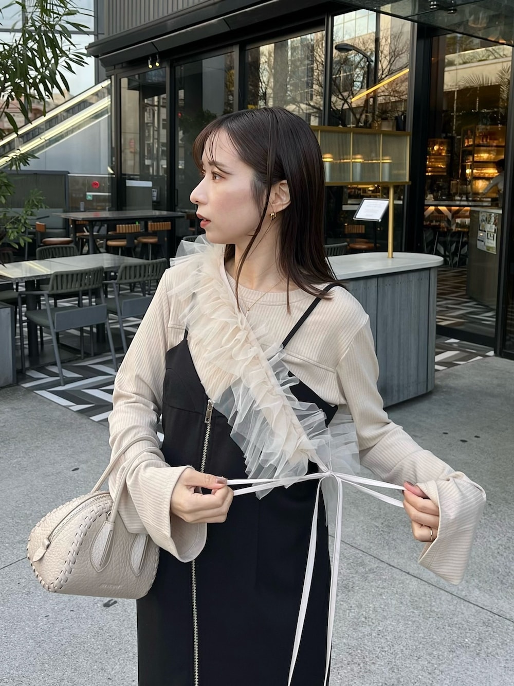 ベージュ系のTシャツ/カットソー、ブラック系のワンピース、ベージュ系のトレンチコートを着用したレディースの冬コーディネートの4枚目の写真