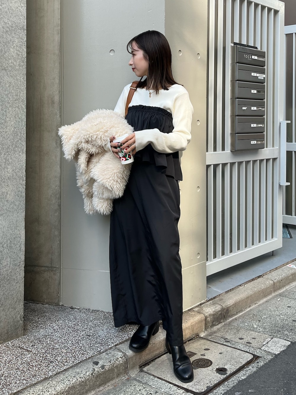 ブラック系のスカート、ホワイト系のニット/セーター、ホワイト系のダウンジャケット/コートを着用したレディースの冬コーディネートの2枚目の写真