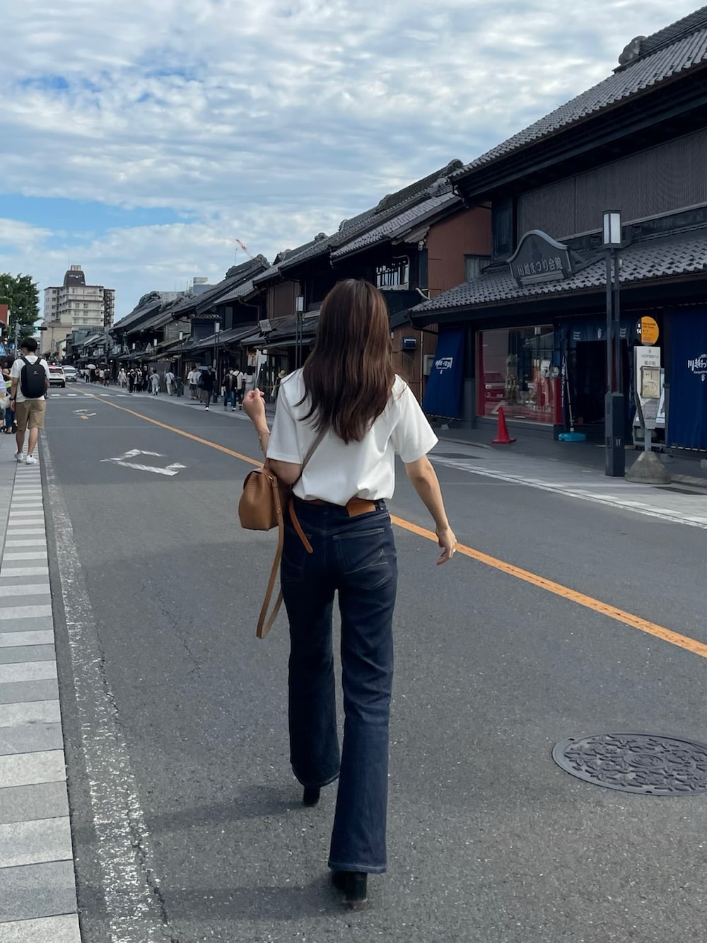 ブルー系のデニムパンツ、ホワイト系のTシャツ/カットソー、ブラウン系のバッグを着用したレディースの夏コーディネートの3枚目の写真