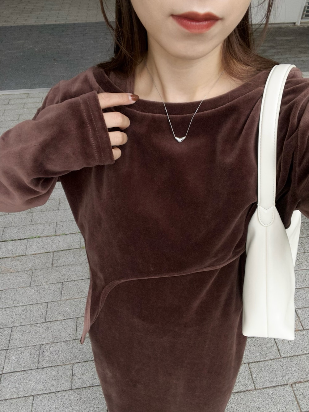 ホワイト系のバッグ、ブラウン系のワンピース、ブラック系のスニーカーを着用したレディースの冬コーディネートの4枚目の写真