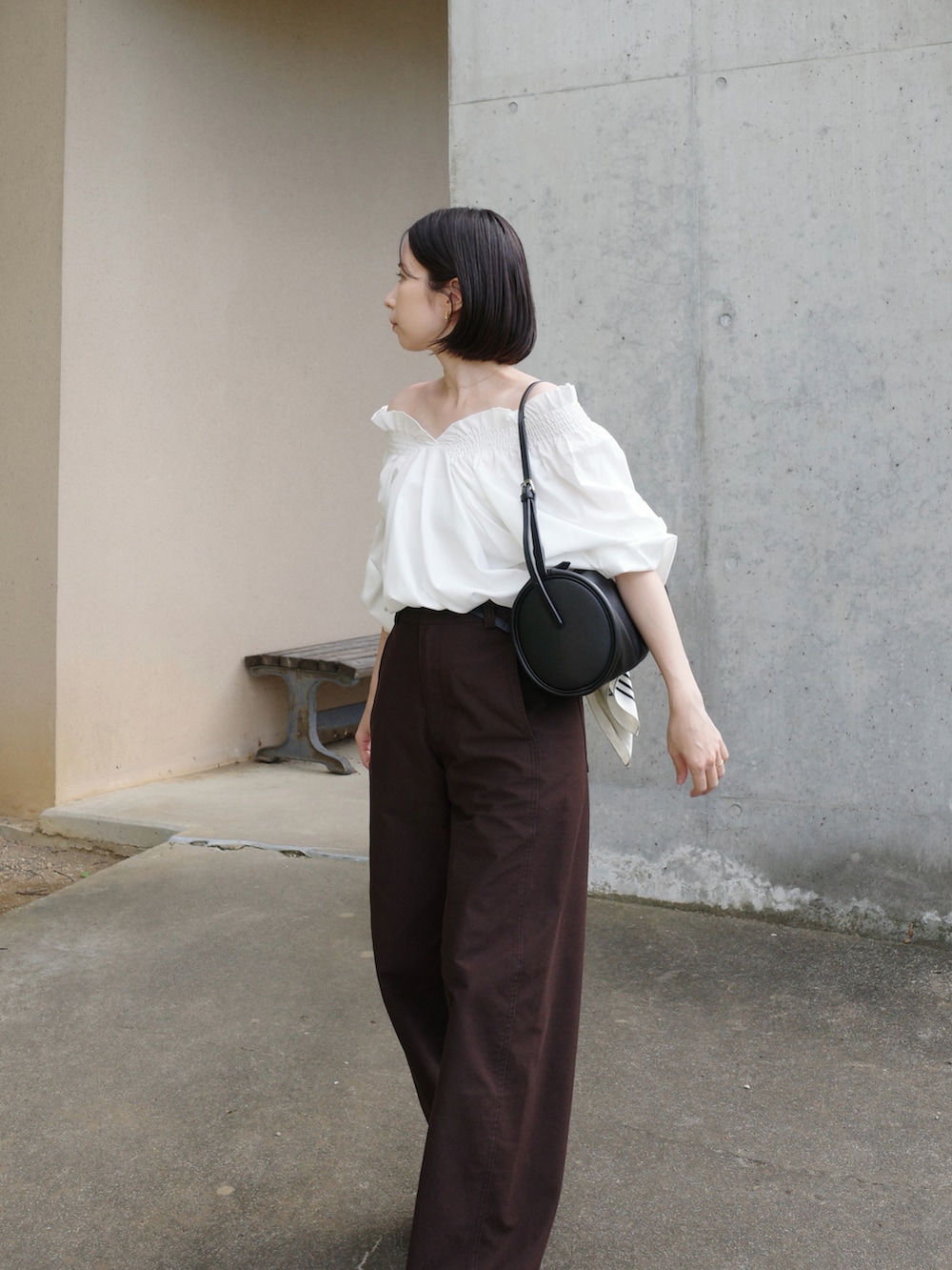 ブラウン系のパンツ、ホワイト系のシャツ/ブラウス、ブラック系のハンドバッグを着用したレディースの秋コーディネートの2枚目の写真