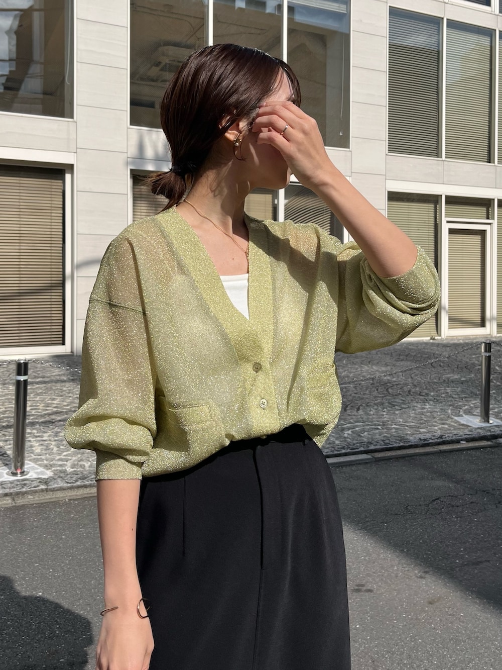 ブラック系のスカート、グリーン系のカーディガン/ボレロ、ホワイト系のハンドバッグを着用したレディースの春コーディネートの5枚目の写真