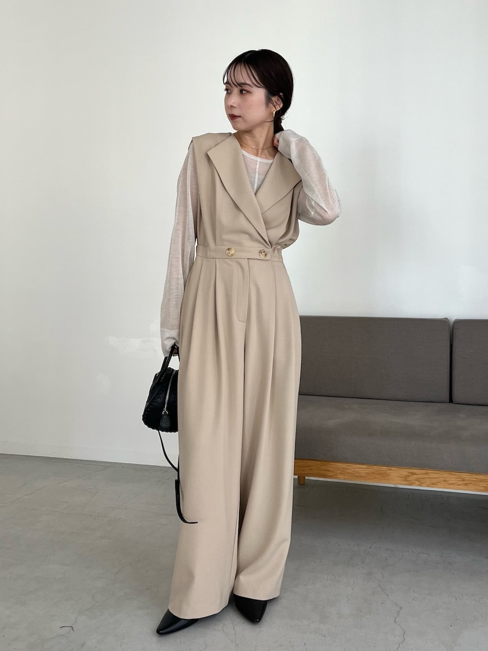 ブラック系のパンプス、ホワイト系のニット/セーター、ベージュ系のつなぎ/オールインワンを着用したレディースの冬コーディネートの2枚目の写真