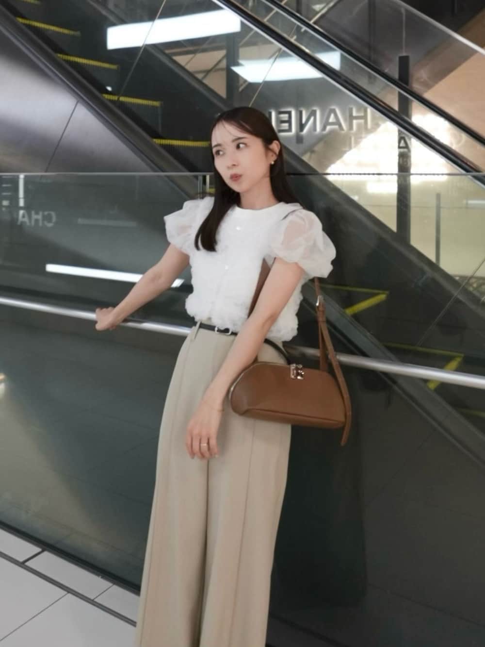 イエロー系のショルダーバッグ、ベージュ系のその他パンツ、ホワイト系のTシャツ/カットソーを着用したレディースの夏コーディネートの3枚目の写真