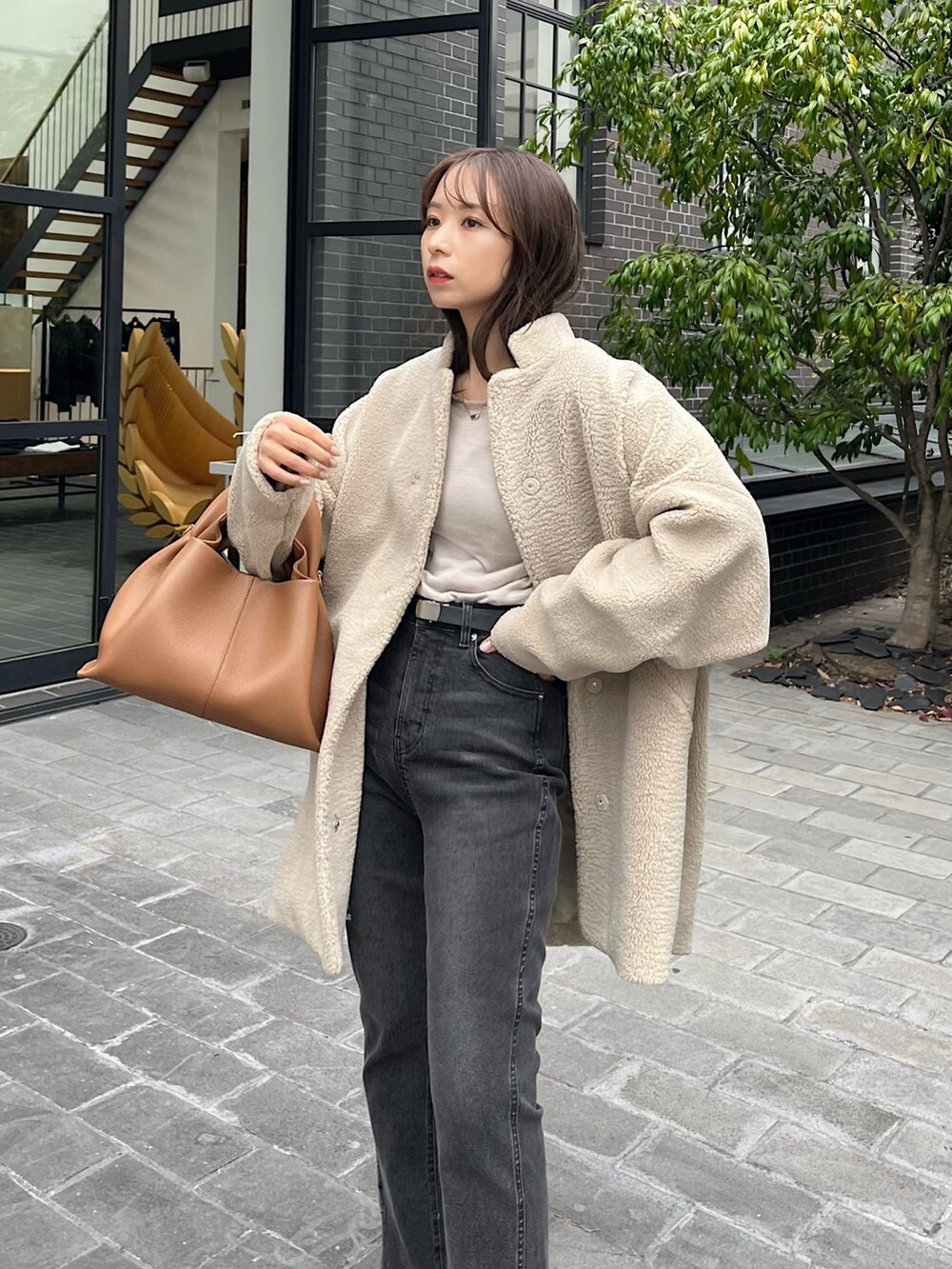 ブラック系のデニムパンツ、ブラウン系のブーツ、ベージュ系のその他アウターを着用したレディースの秋コーディネートの3枚目の写真