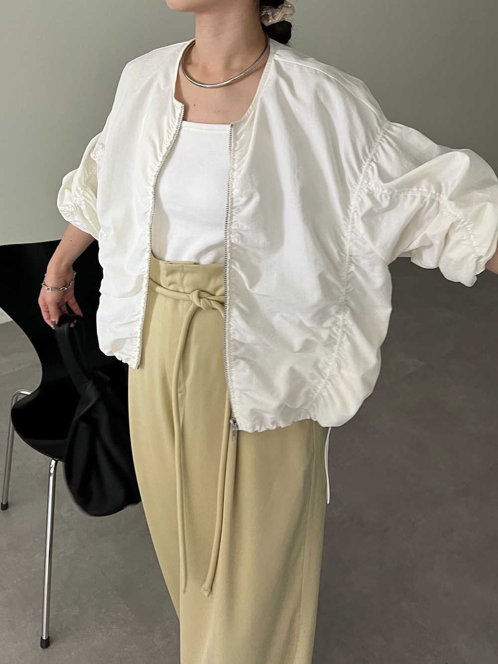 ブラック系のハンドバッグ、グリーン系のその他パンツ、ホワイト系のキャミソールを着用したレディースの春コーディネートの5枚目の写真