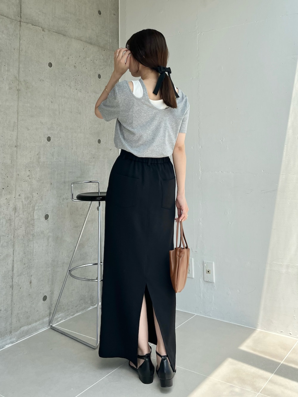 ブラック系のスカート、グレー系のTシャツ/カットソー、ブラック系のサンダルを着用したレディースの夏コーディネートの3枚目の写真