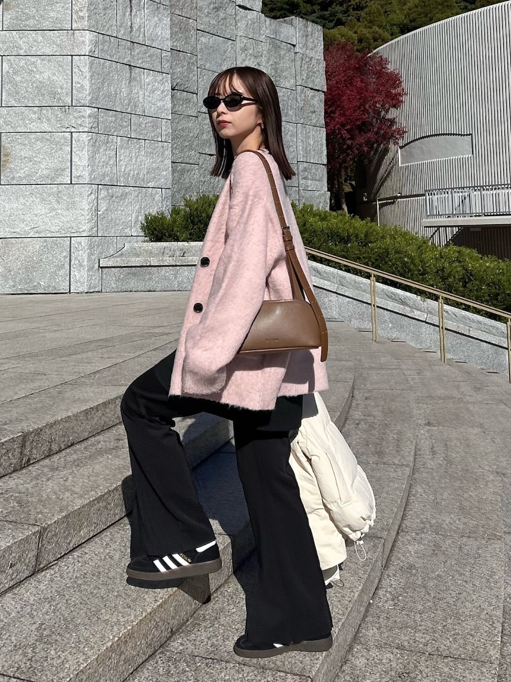 イエロー系のショルダーバッグ、ピンク系のカーディガン/ボレロ、ブラック系のスニーカーを着用したレディースの冬コーディネートの3枚目の写真