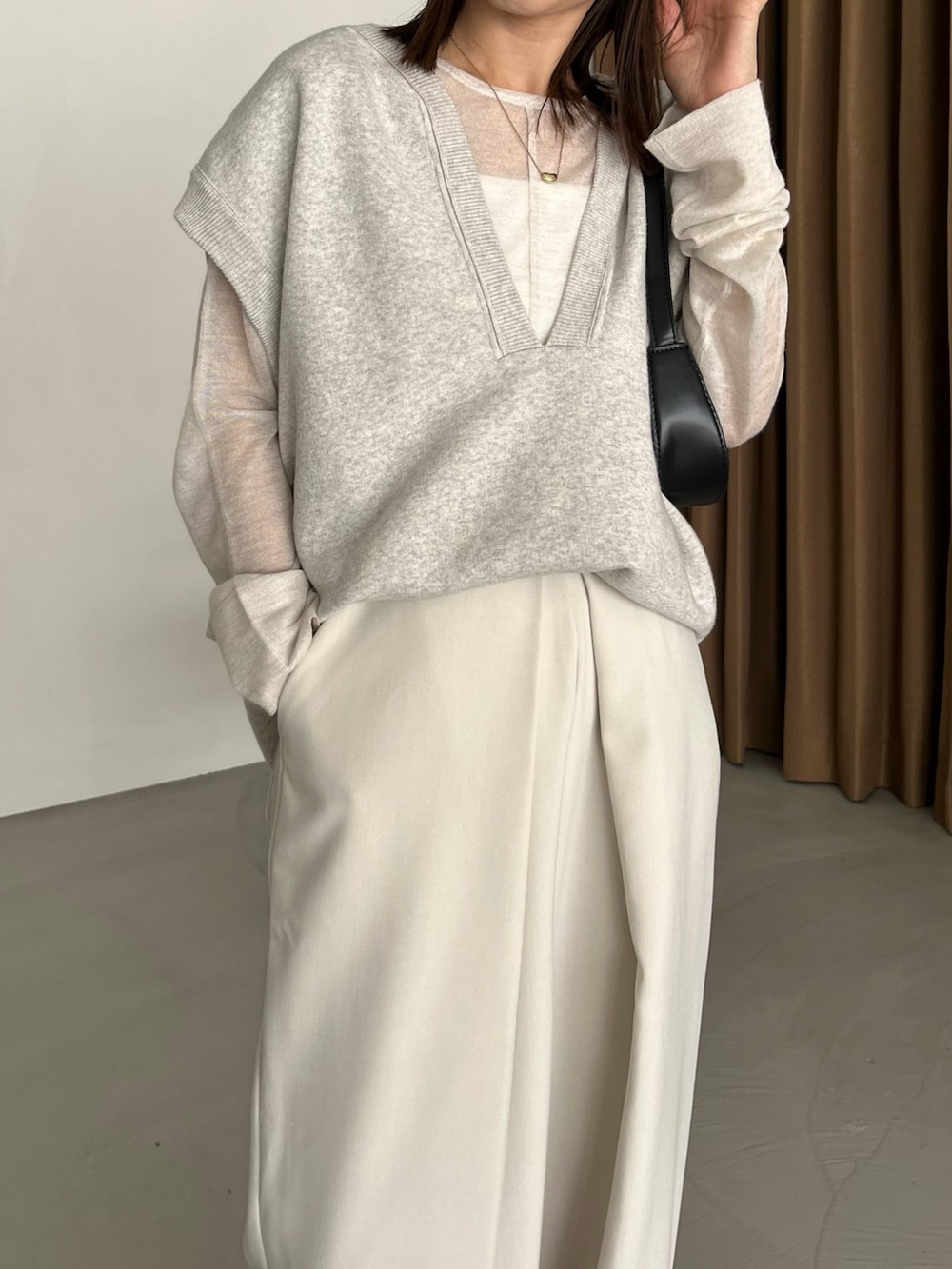 グレー系のベスト、ホワイト系のニット/セーター、ブラック系のパンプスを着用したレディースの秋コーディネートの5枚目の写真