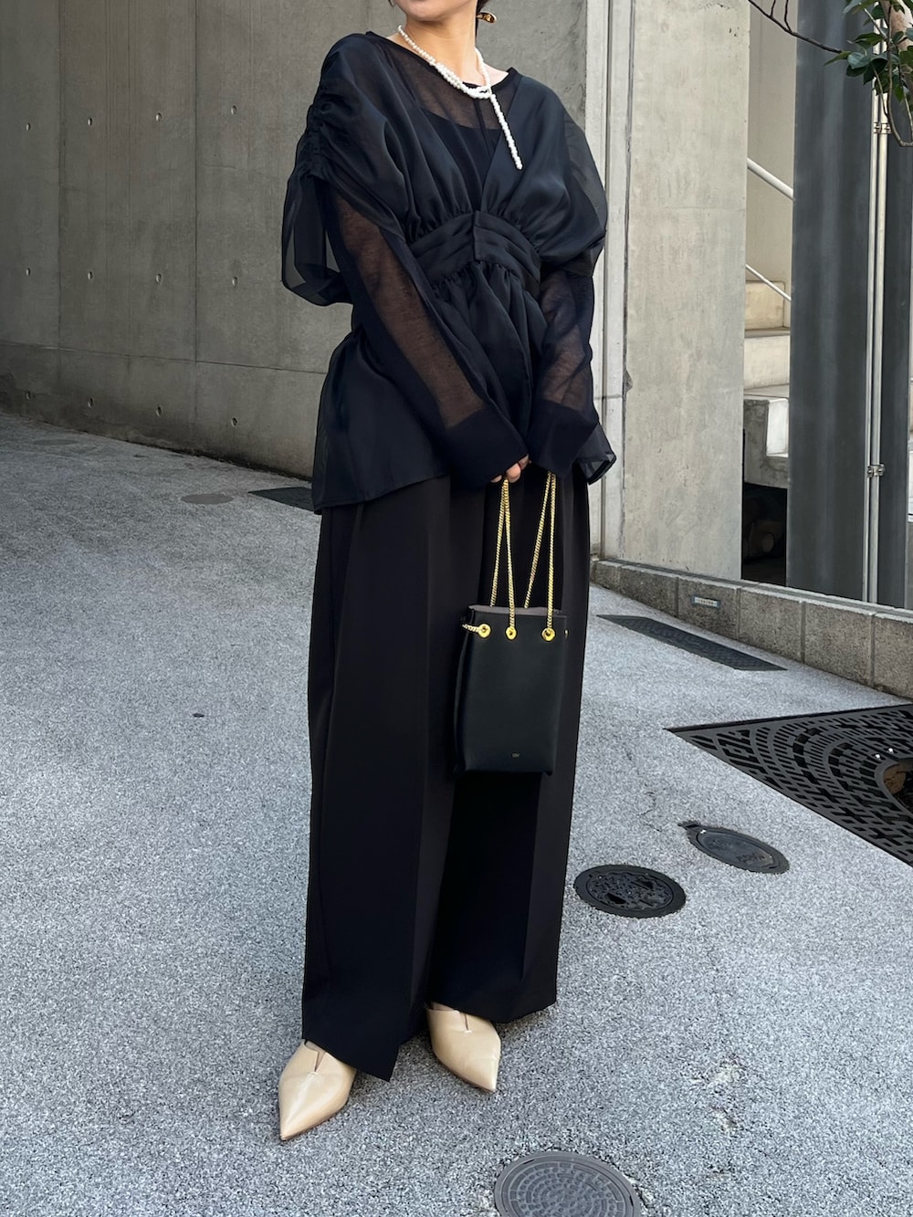 ブラック系のニット/セーター、ブラック系のシャツ/ブラウス、ブラック系のショルダーバッグを着用したレディースの冬コーディネートの2枚目の写真