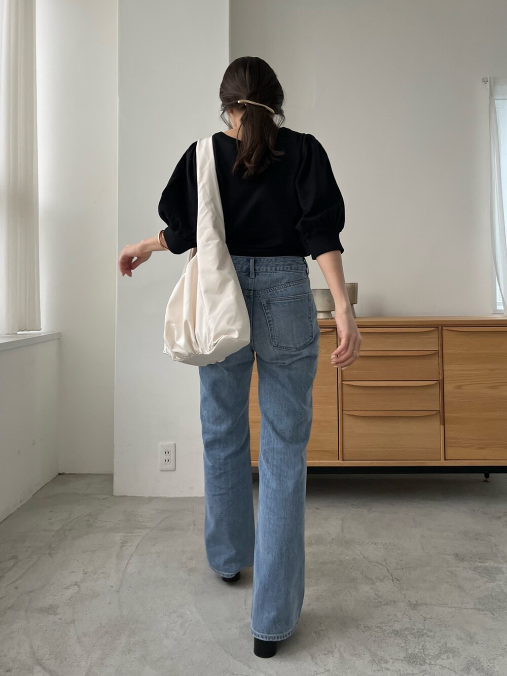 ブルー系のデニムパンツ、ホワイト系のバッグ、ブラック系のニット/セーターを着用したレディースの春コーディネートの3枚目の写真