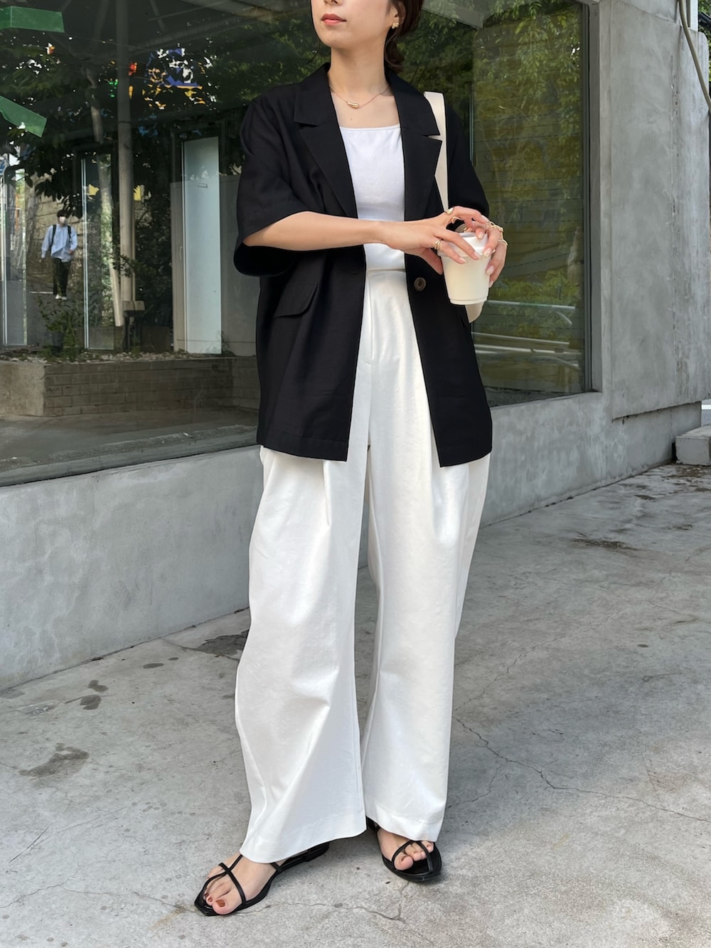 ブラック系のテーラードジャケット、ホワイト系のバッグ、ホワイト系のキャミソールを着用したレディースの春コーディネートの7枚目の写真