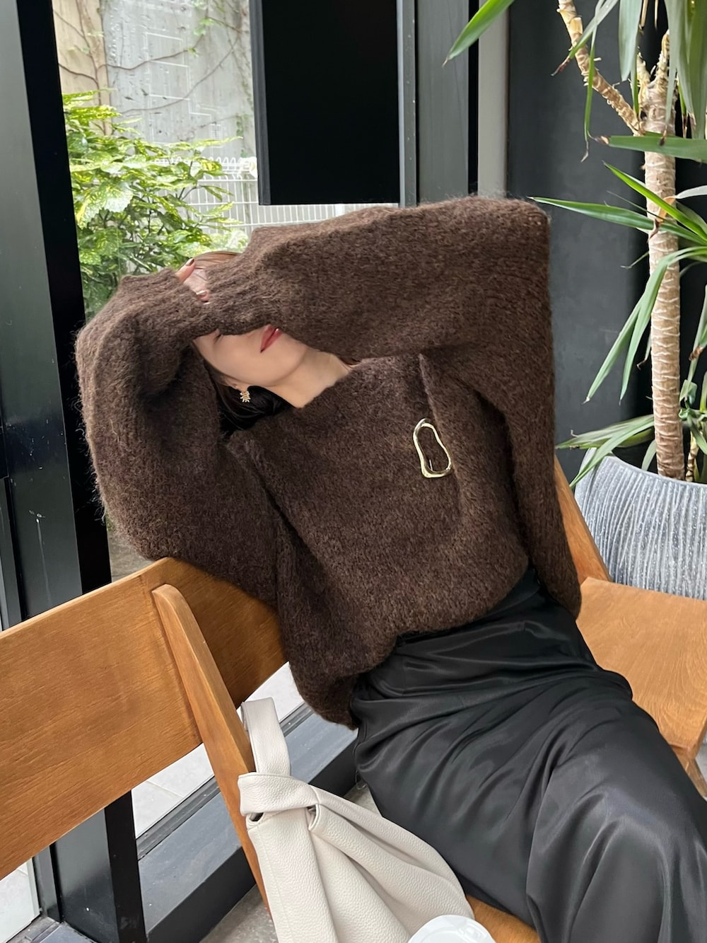 ブラック系のスカート、ブラウン系のニット/セーター、ホワイト系のハンドバッグを着用したレディースの秋コーディネートの5枚目の写真