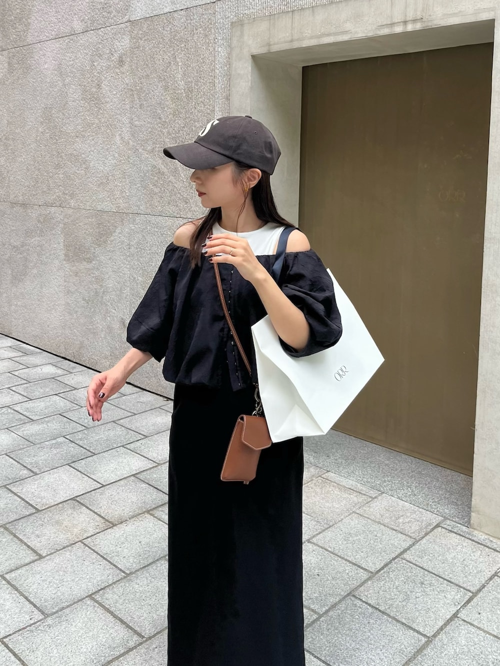 ブラック系のスカート、ブラック系のシャツ/ブラウス、ブラウン系のショルダーバッグを着用したレディースの秋コーディネートの3枚目の写真