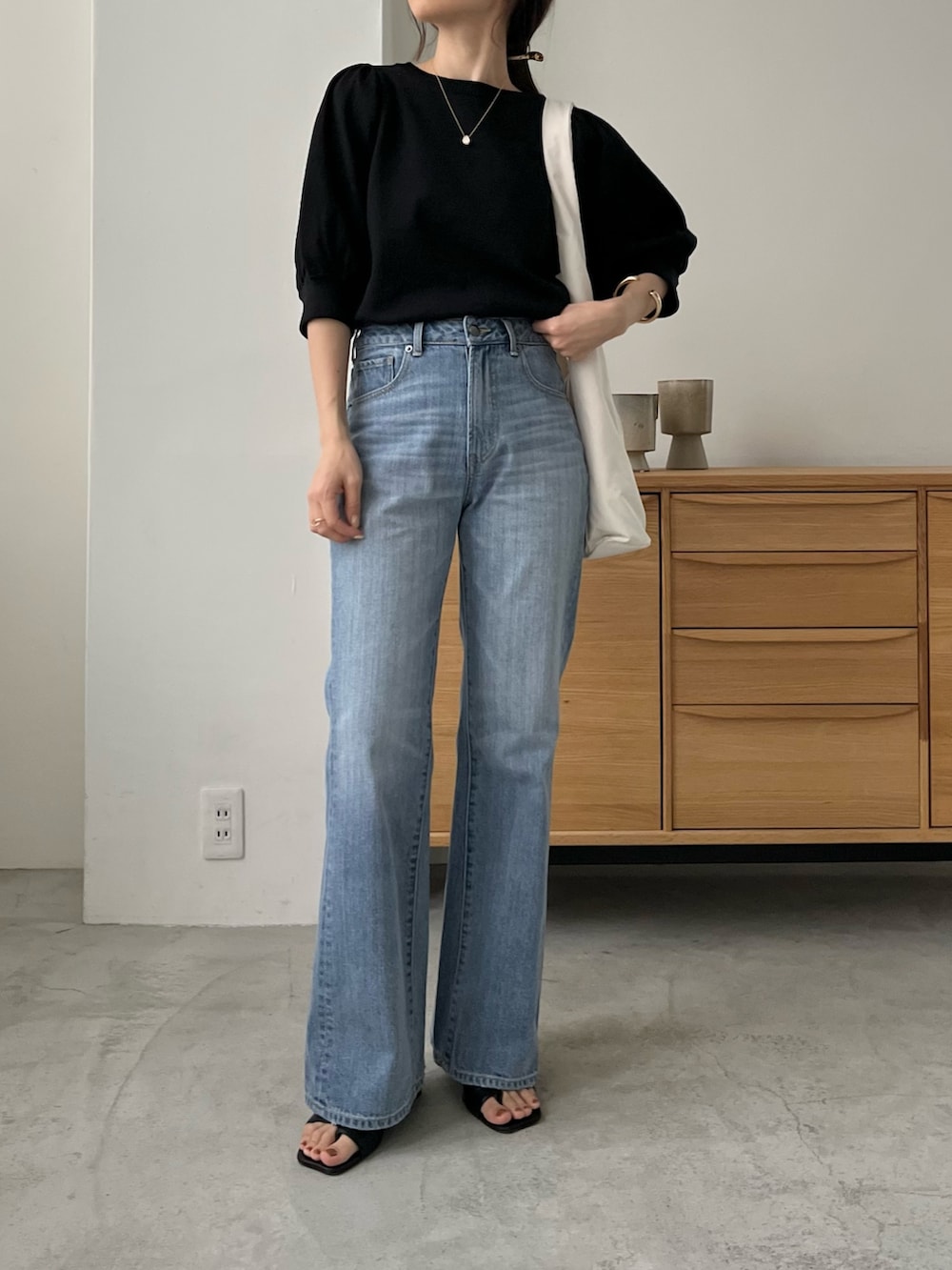 ブルー系のデニムパンツ、ホワイト系のバッグ、ブラック系のニット/セーターを着用したレディースの春コーディネートの2枚目の写真