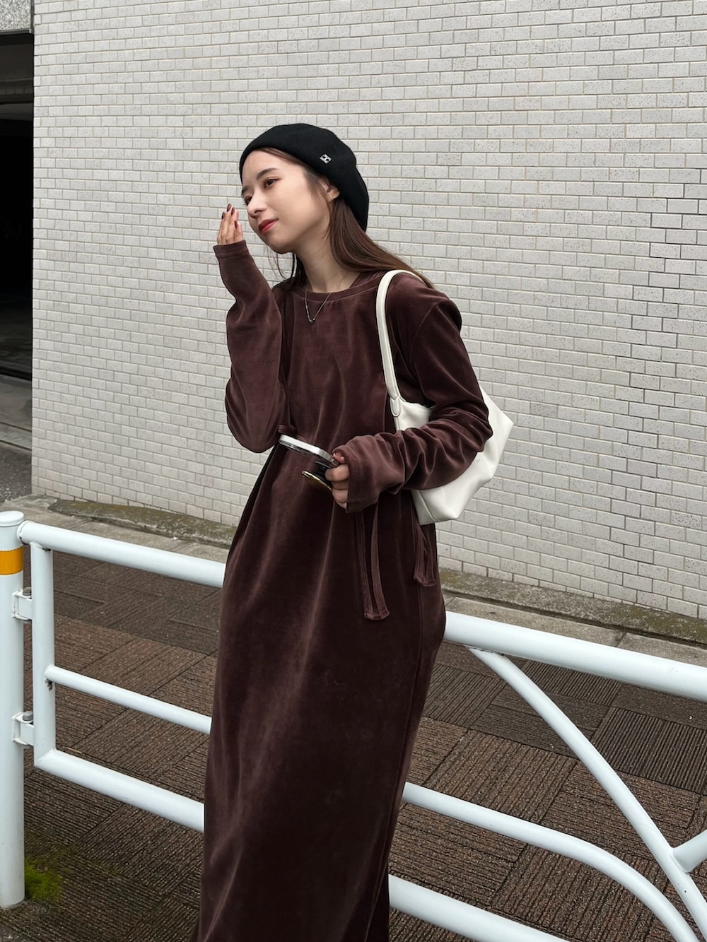 ホワイト系のバッグ、ブラウン系のワンピース、ブラック系のスニーカーを着用したレディースの冬コーディネートの3枚目の写真