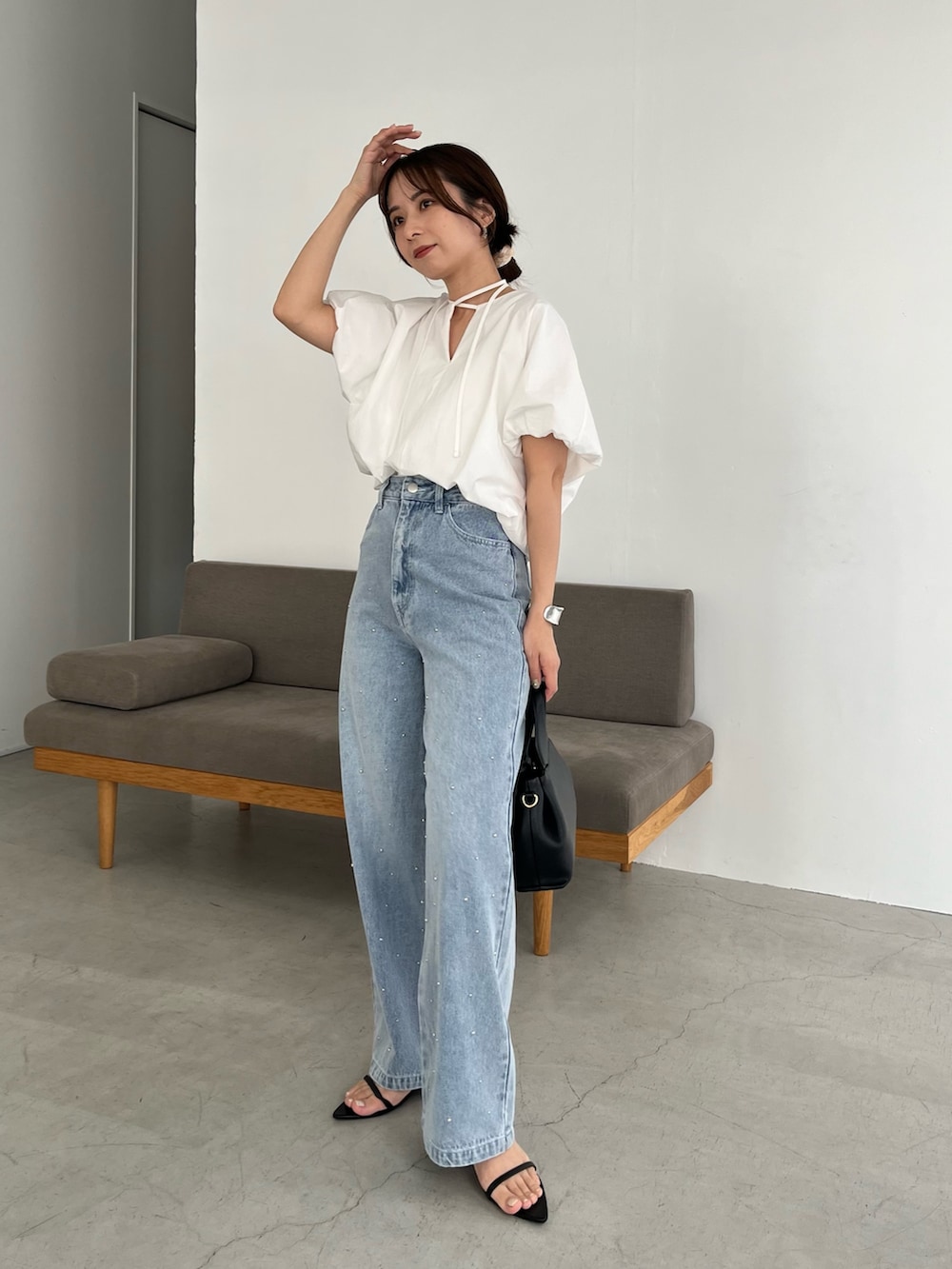 ブルー系のデニムパンツ、ホワイト系のシャツ/ブラウス、ブラック系のショルダーバッグを着用したレディースの春コーディネートの2枚目の写真