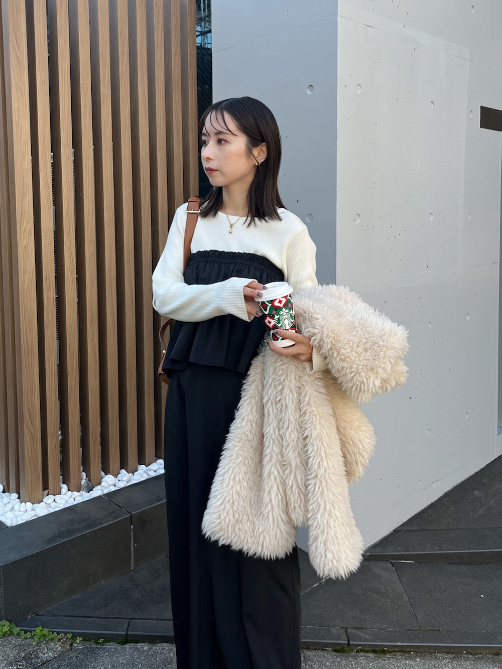 ブラック系のスカート、ホワイト系のニット/セーター、ホワイト系のダウンジャケット/コートを着用したレディースの冬コーディネートの3枚目の写真
