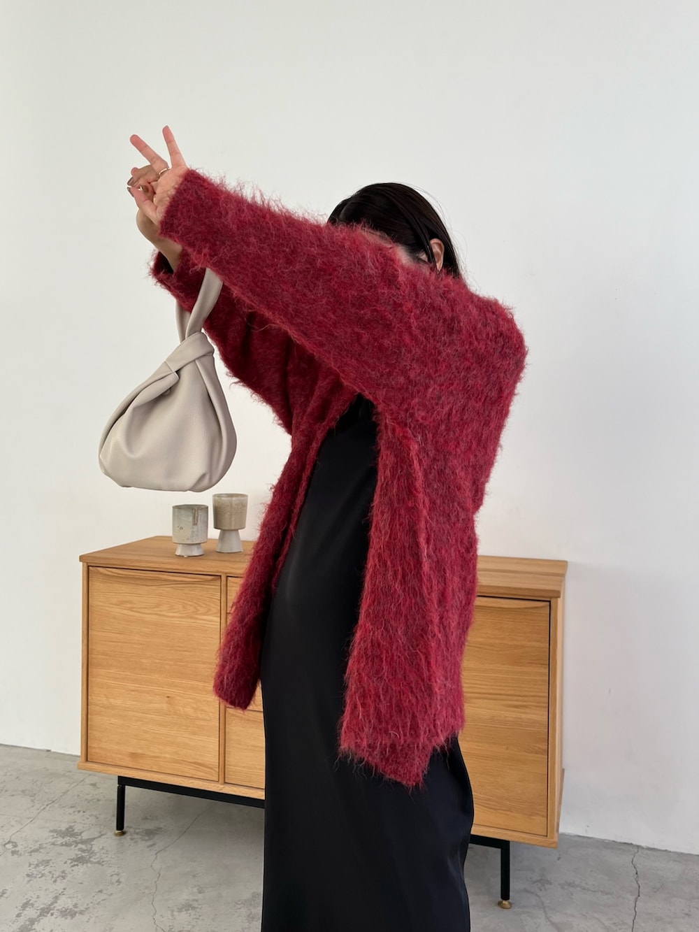 レッド系のカーディガン/ボレロ、ブラック系のワンピース、ホワイト系のハンドバッグを着用したレディースの冬コーディネートの4枚目の写真