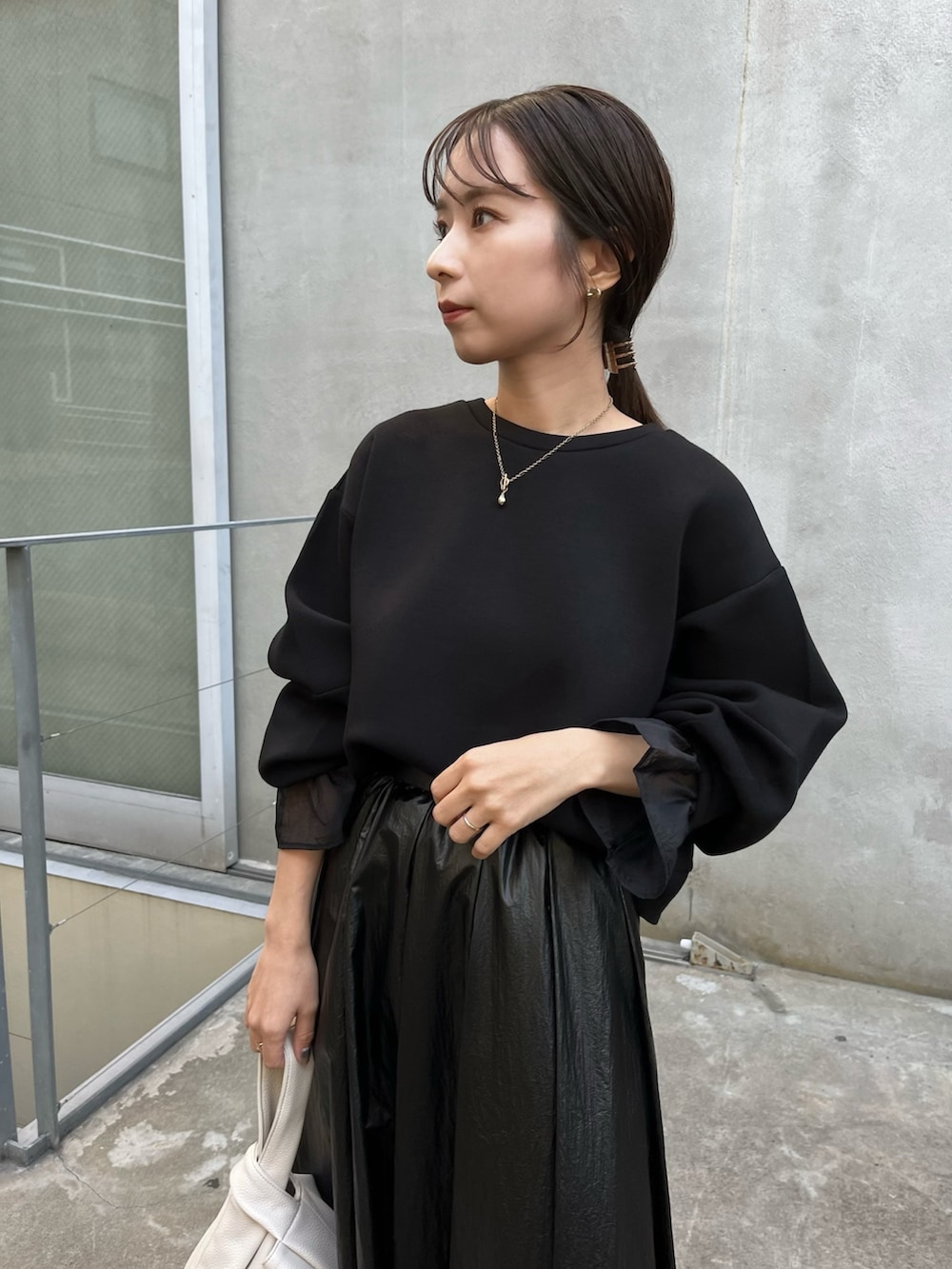 ブラック系のスカート、ブラック系のスウェット、ホワイト系のハンドバッグを着用したレディースの冬コーディネートの4枚目の写真