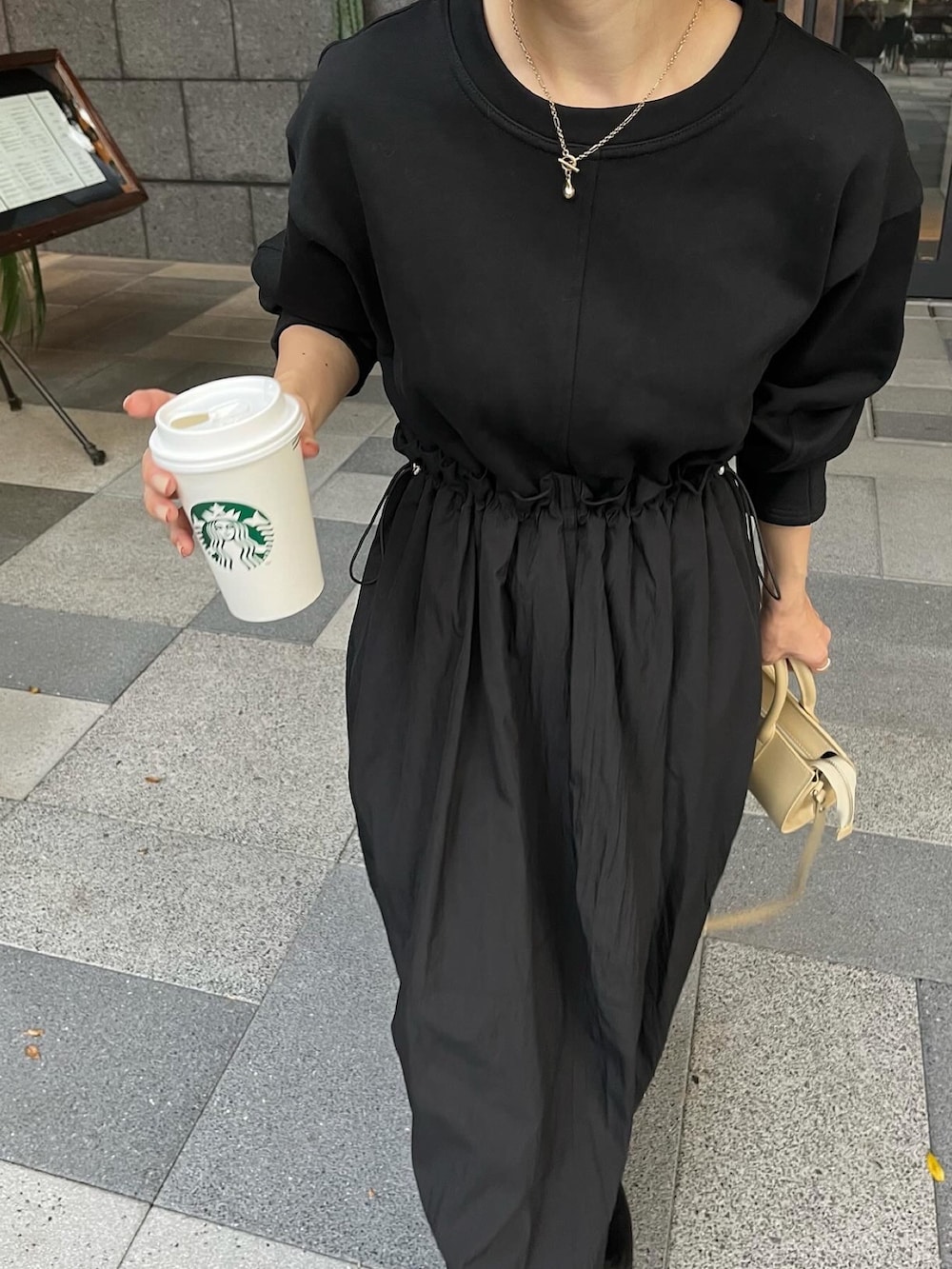 ブラック系のワンピース、ベージュ系のバッグ、ブラック系のブーツを着用したレディースの秋コーディネートの5枚目の写真