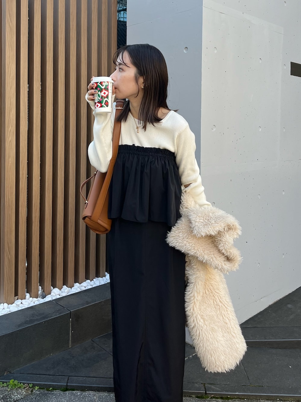 ブラック系のスカート、ホワイト系のニット/セーター、ホワイト系のダウンジャケット/コートを着用したレディースの冬コーディネートの4枚目の写真