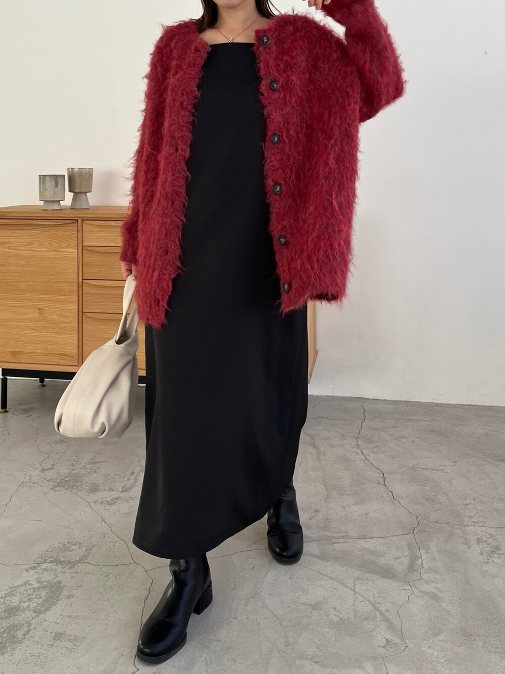 レッド系のカーディガン/ボレロ、ブラック系のワンピース、ホワイト系のハンドバッグを着用したレディースの冬コーディネートの2枚目の写真