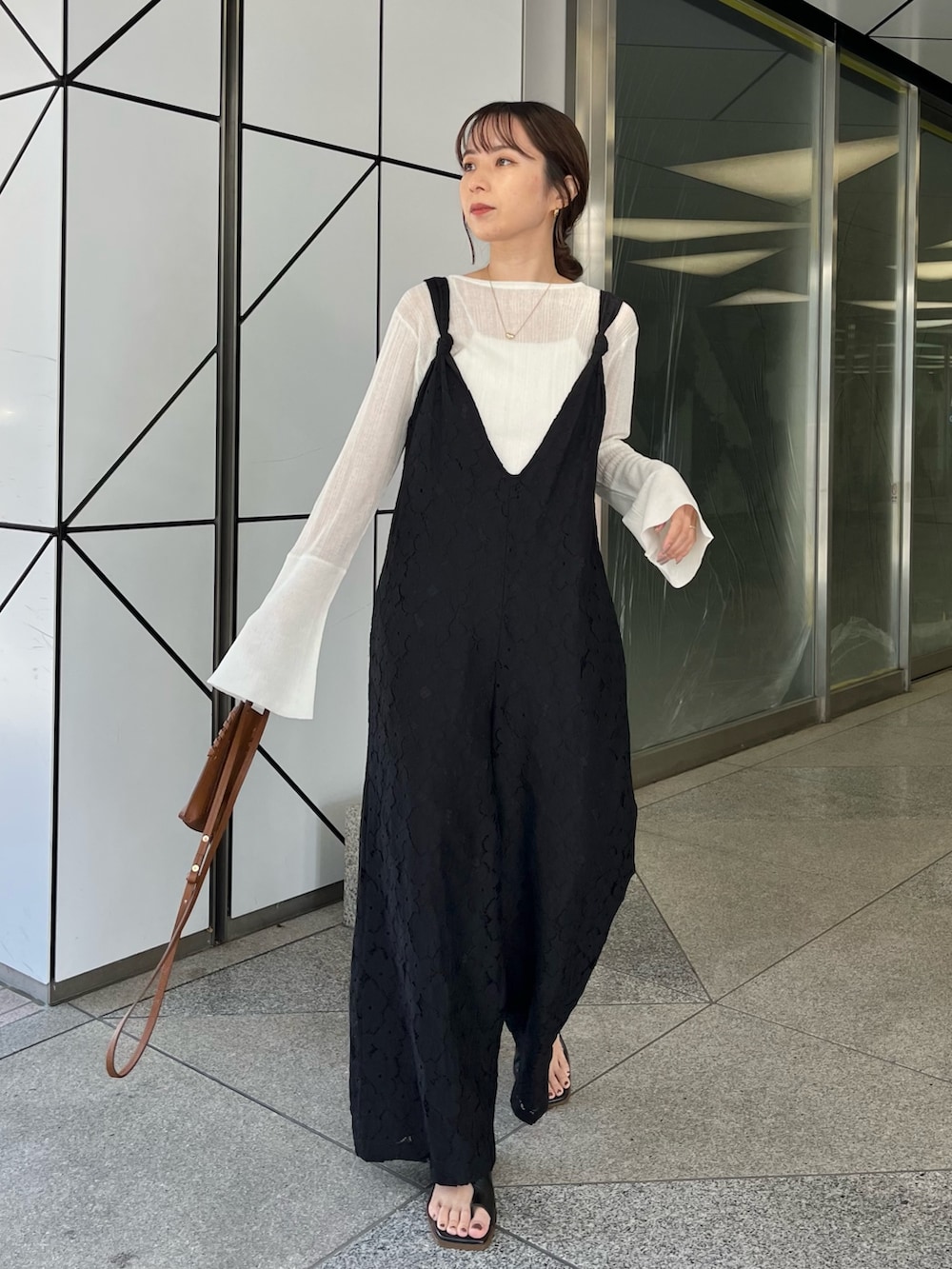 ホワイト系のニット/セーター、ブラック系のサロペット/オーバーオール、ブラウン系のトートバッグを着用したレディースの冬コーディネートの2枚目の写真