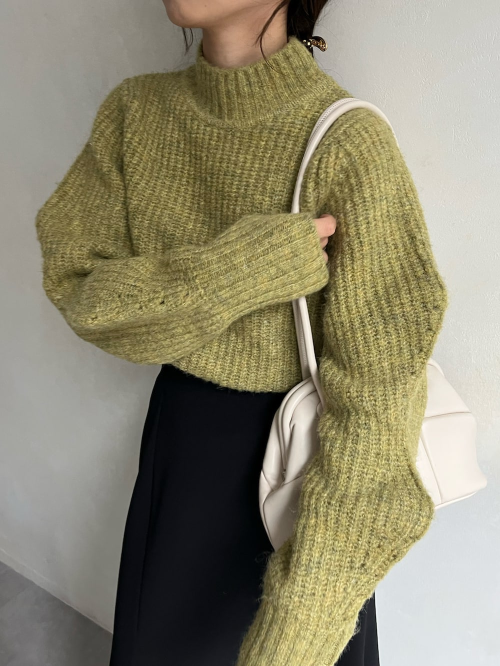 グリーン系のニット/セーター、ブラック系のスカート、ブラック系のブーツを着用したレディースの冬コーディネートの4枚目の写真