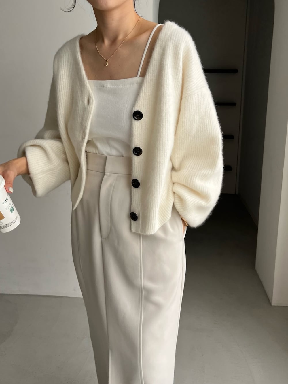 ホワイト系のカーディガン/ボレロ、ブラック系のパンプス、ホワイト系のスカートを着用したレディースの秋コーディネートの6枚目の写真