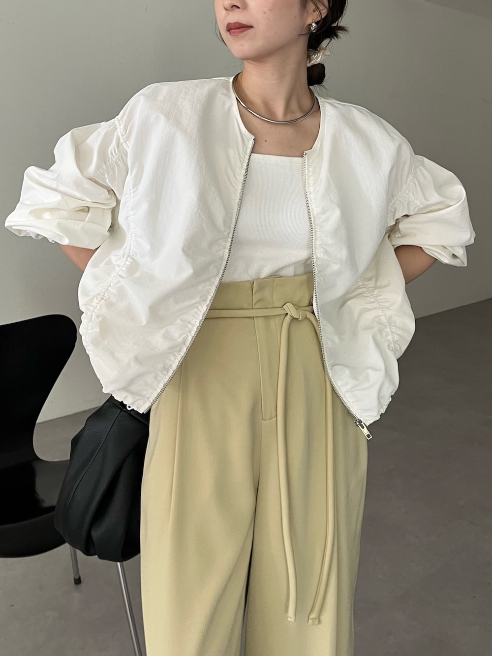 ブラック系のハンドバッグ、グリーン系のその他パンツ、ホワイト系のキャミソールを着用したレディースの春コーディネートの7枚目の写真