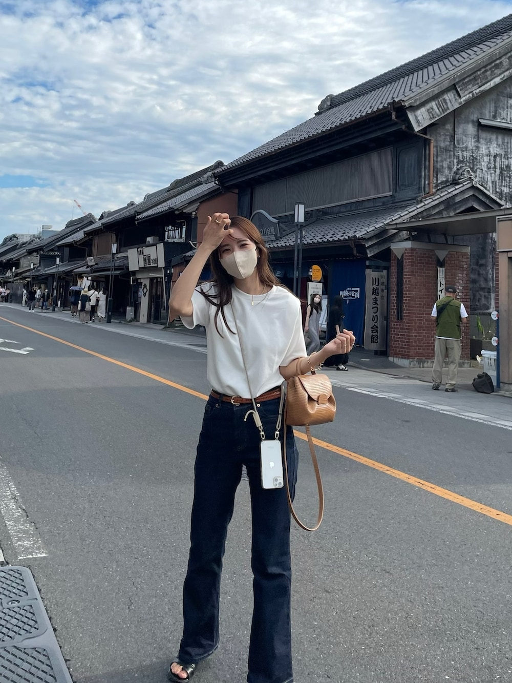 ブルー系のデニムパンツ、ホワイト系のTシャツ/カットソー、ブラウン系のバッグを着用したレディースの夏コーディネートの2枚目の写真