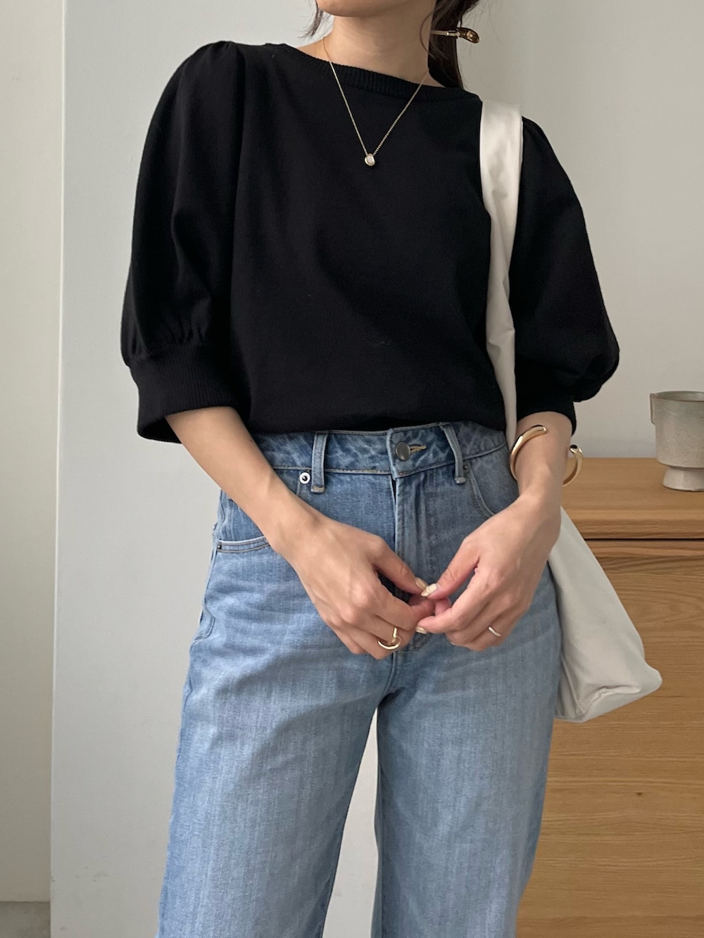ブルー系のデニムパンツ、ホワイト系のバッグ、ブラック系のニット/セーターを着用したレディースの春コーディネートの5枚目の写真