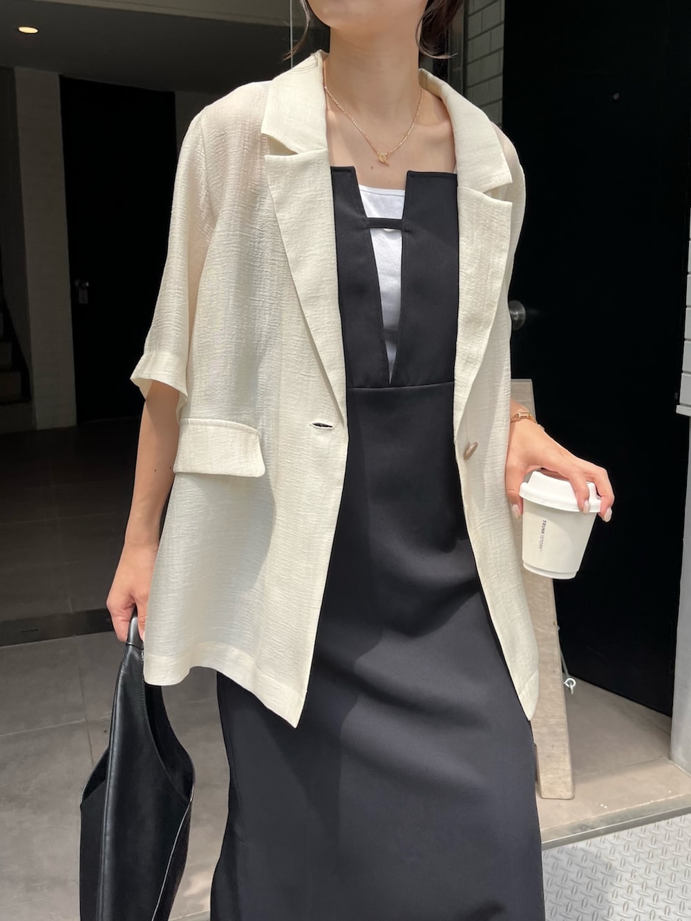 ブラック系のワンピース、ブラック系のその他シューズ、ホワイト系のテーラードジャケットを着用したレディースの春コーディネートの5枚目の写真