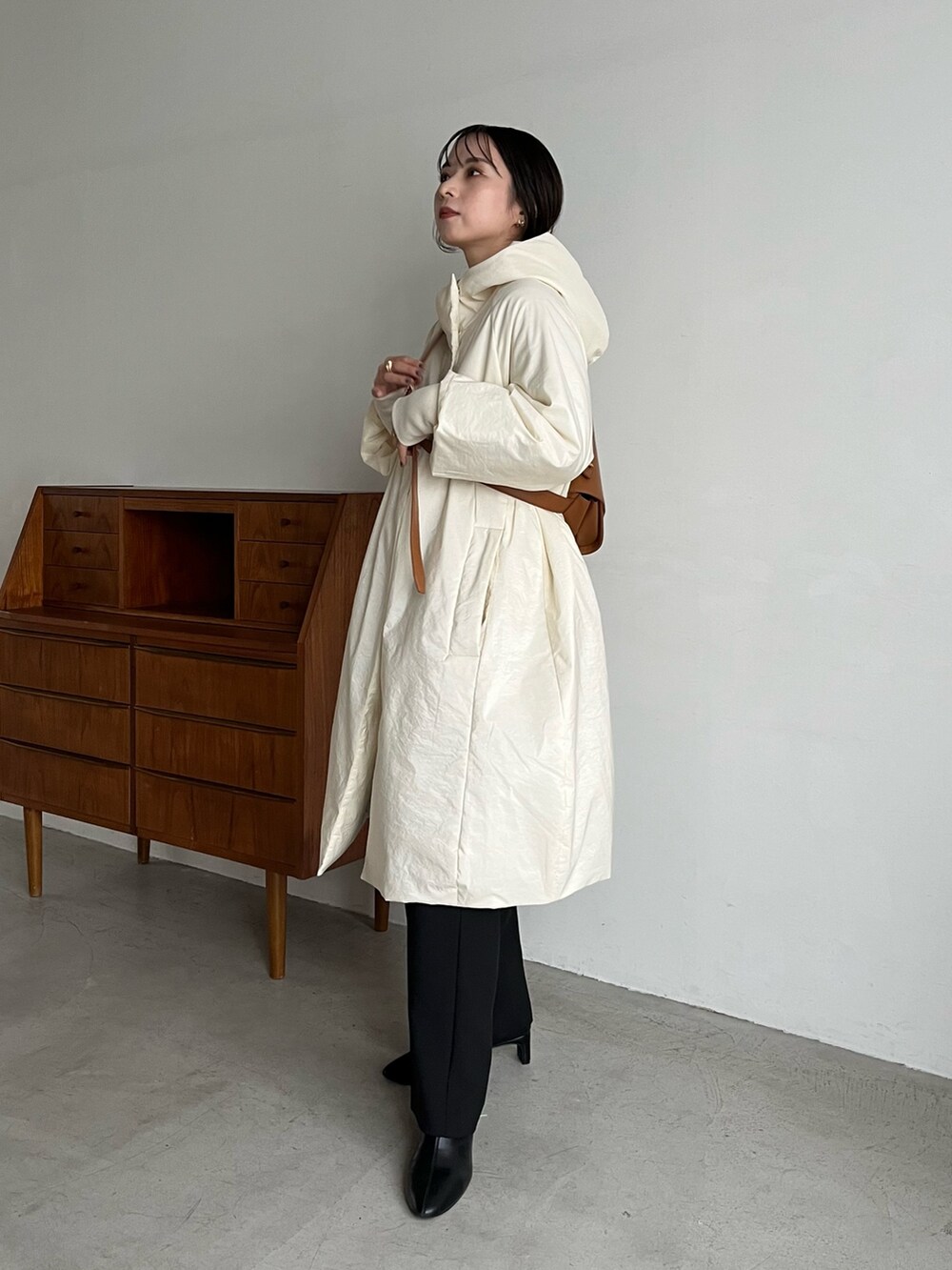 ブラック系のスラックス、ベージュ系のショルダーバッグ、ホワイト系のダウンジャケット/コートを着用したレディースの冬コーディネートの3枚目の写真