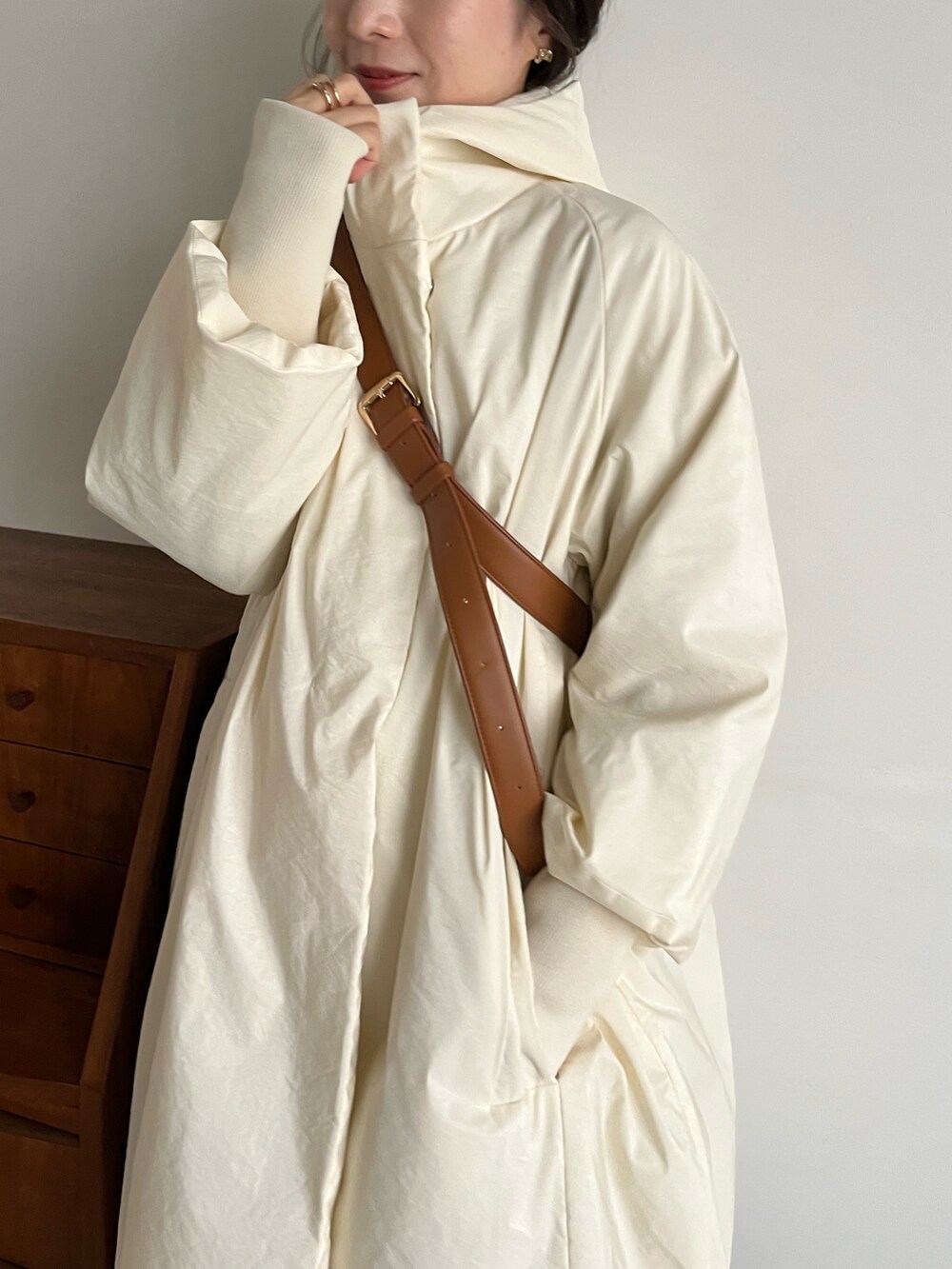 ブラック系のスラックス、ベージュ系のショルダーバッグ、ホワイト系のダウンジャケット/コートを着用したレディースの冬コーディネートの5枚目の写真