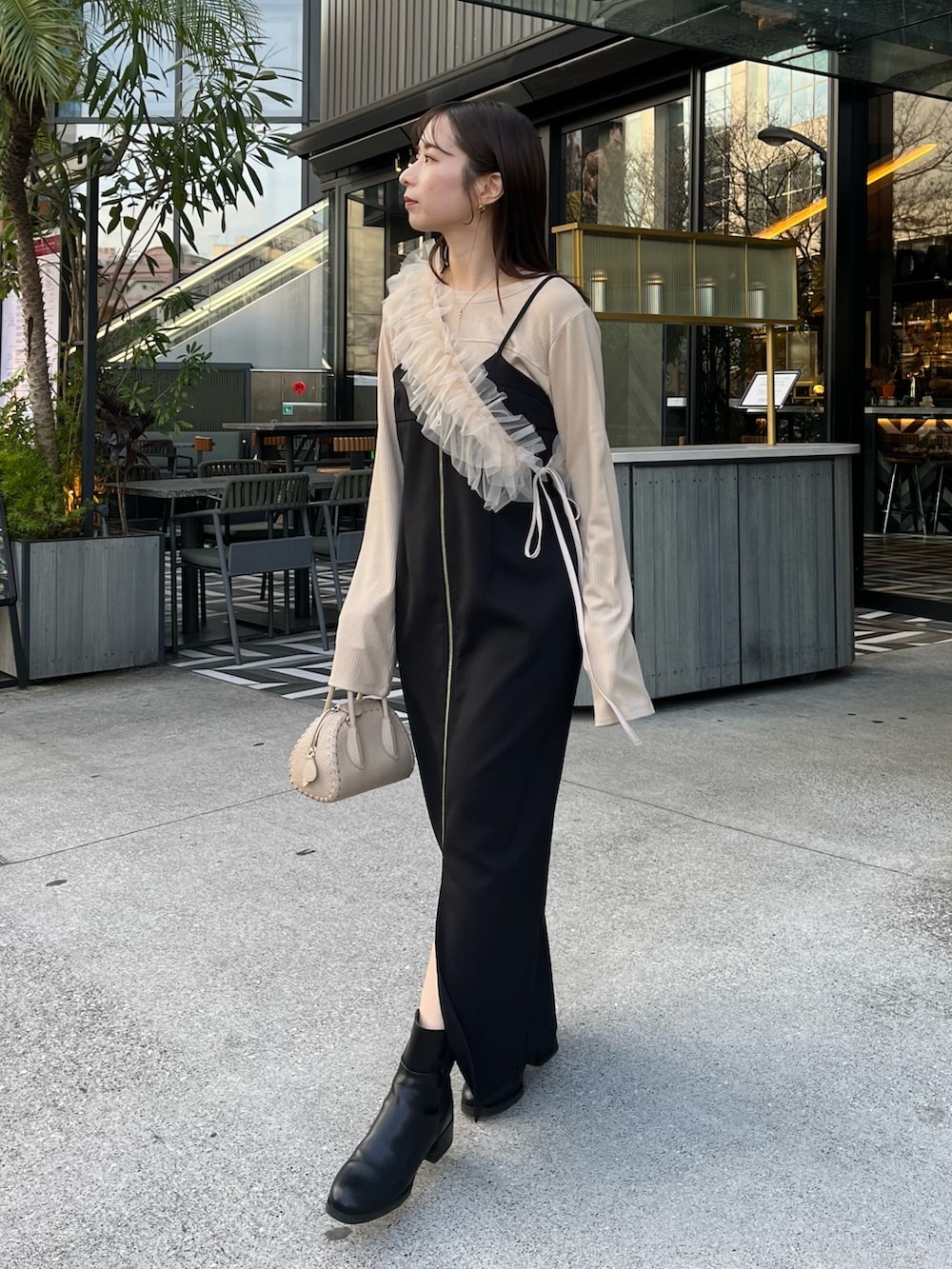 ベージュ系のTシャツ/カットソー、ブラック系のワンピース、ベージュ系のトレンチコートを着用したレディースの冬コーディネートの5枚目の写真