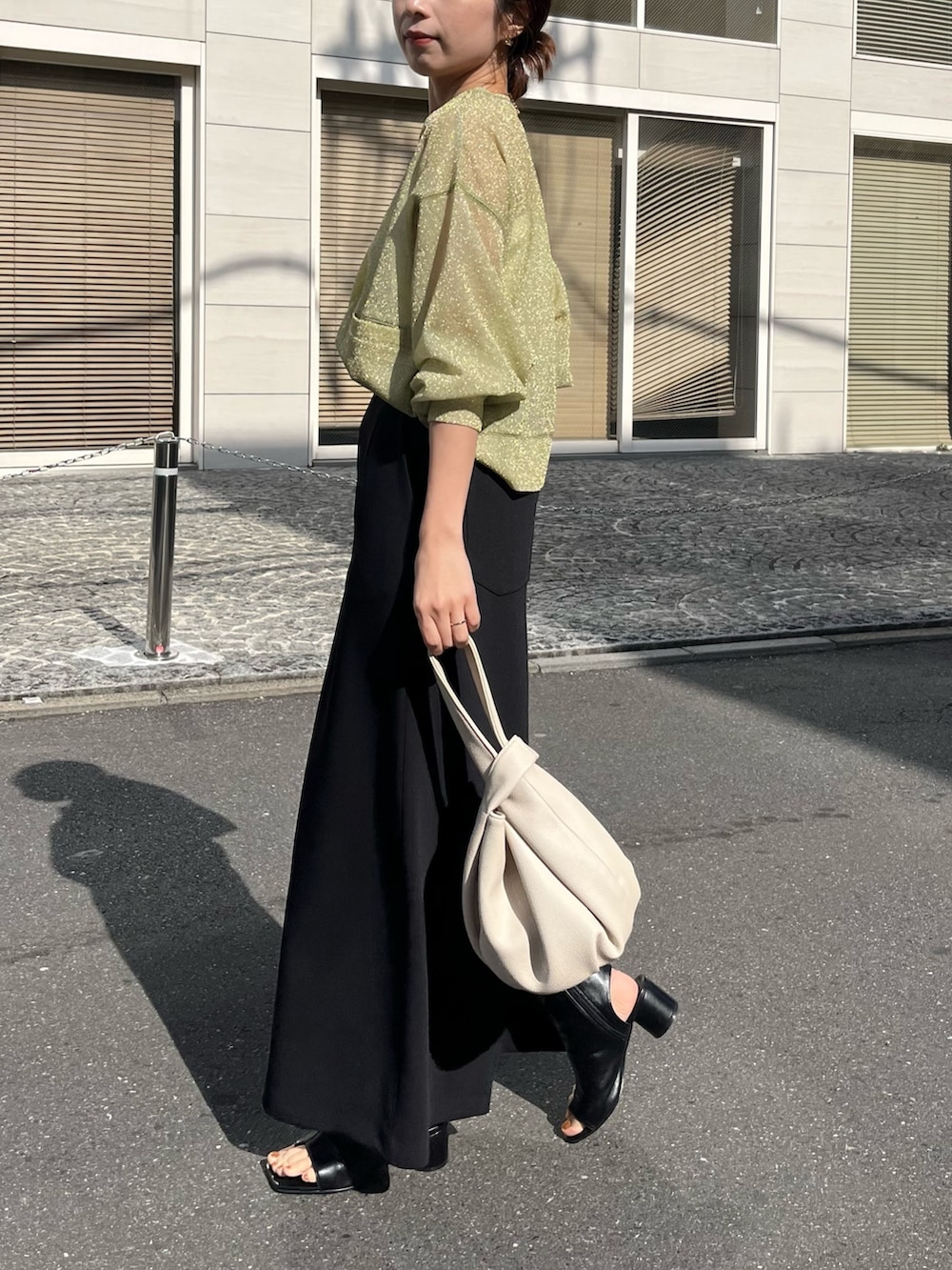 ブラック系のスカート、グリーン系のカーディガン/ボレロ、ホワイト系のハンドバッグを着用したレディースの春コーディネートの3枚目の写真