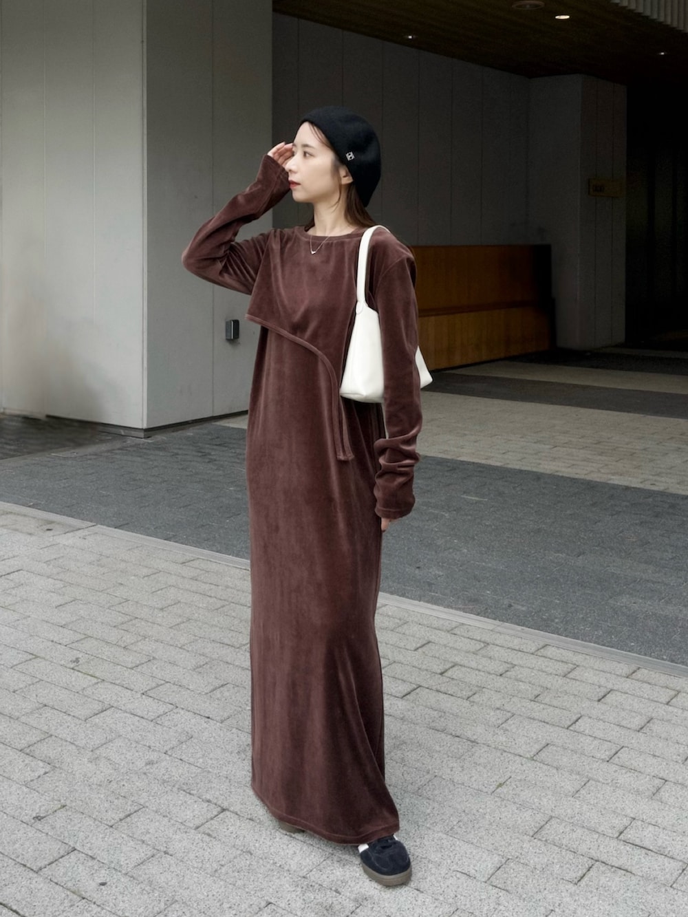 ホワイト系のバッグ、ブラウン系のワンピース、ブラック系のスニーカーを着用したレディースの冬コーディネートの6枚目の写真