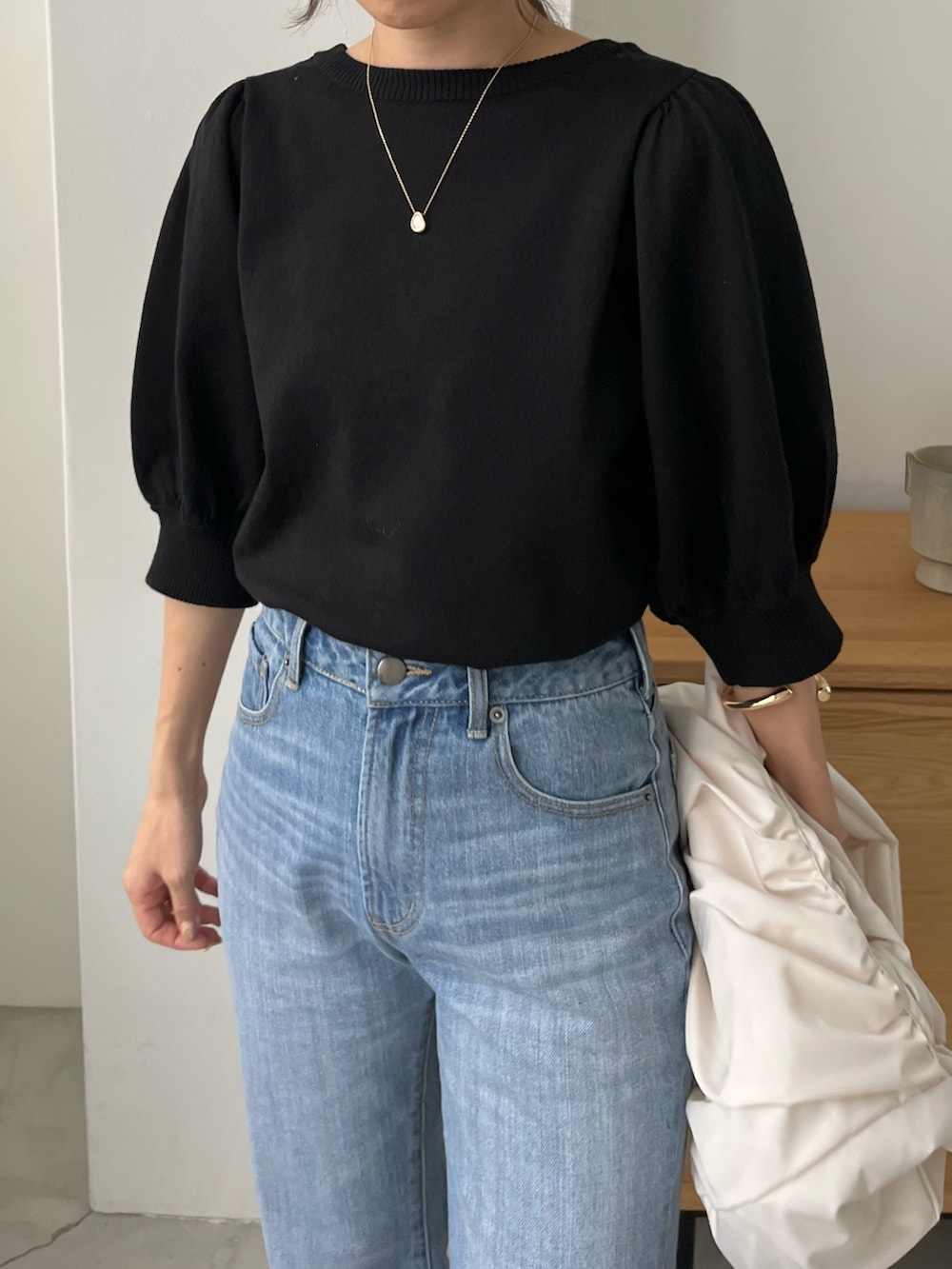 ブルー系のデニムパンツ、ホワイト系のバッグ、ブラック系のニット/セーターを着用したレディースの春コーディネートの6枚目の写真