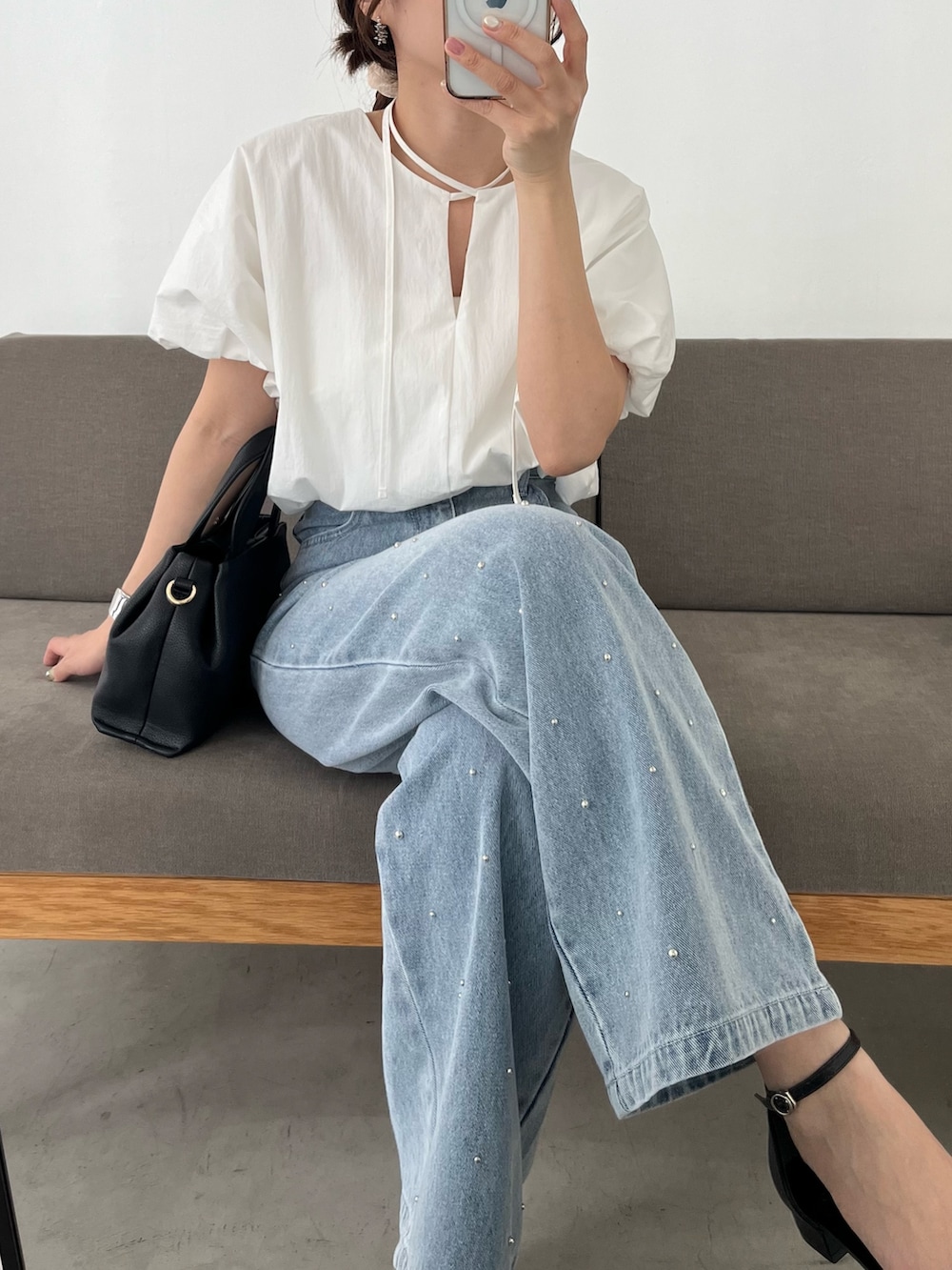 ブルー系のデニムパンツ、ホワイト系のシャツ/ブラウス、ブラック系のショルダーバッグを着用したレディースの春コーディネートの3枚目の写真