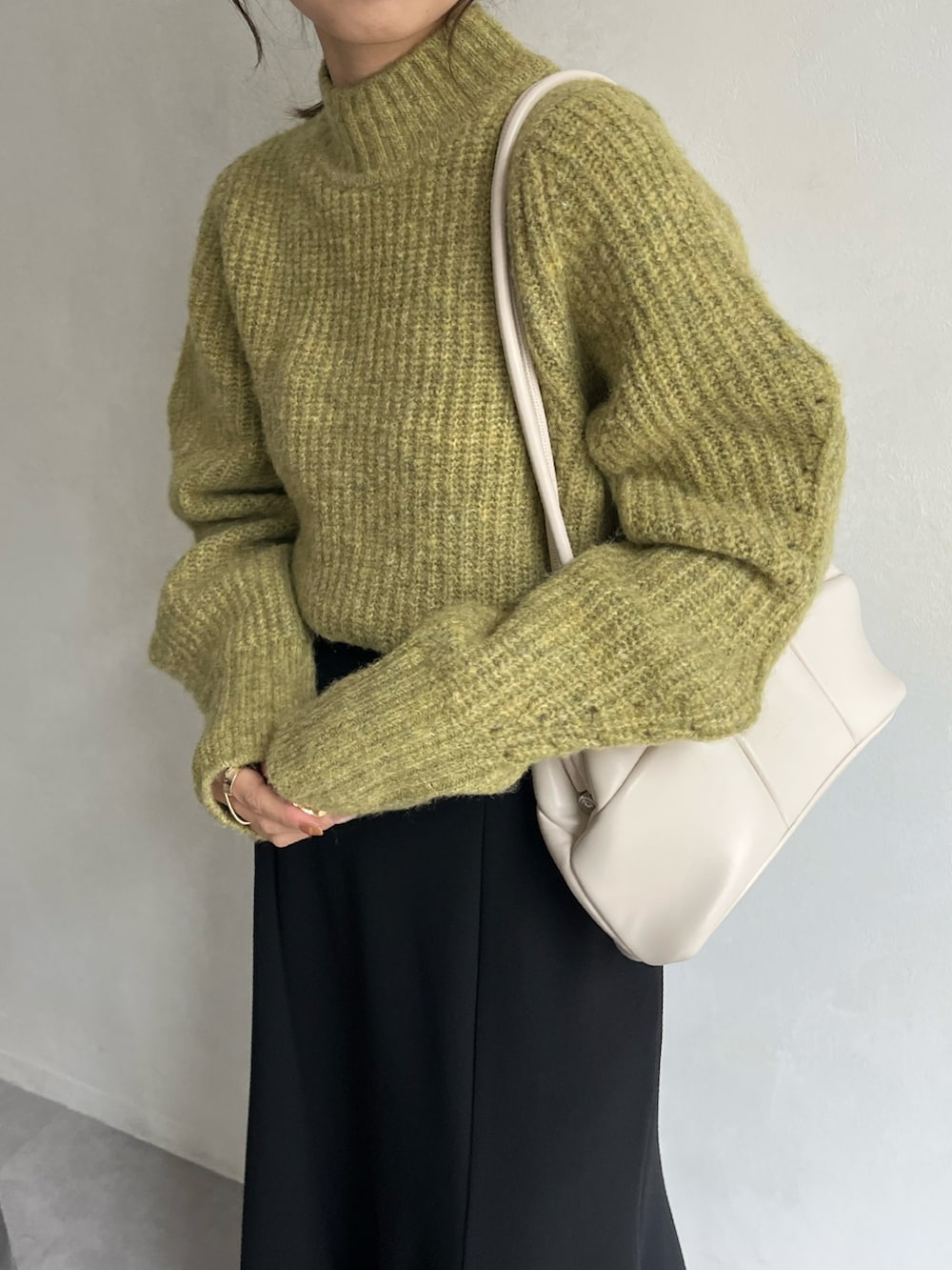 グリーン系のニット/セーター、ブラック系のスカート、ブラック系のブーツを着用したレディースの冬コーディネートの3枚目の写真