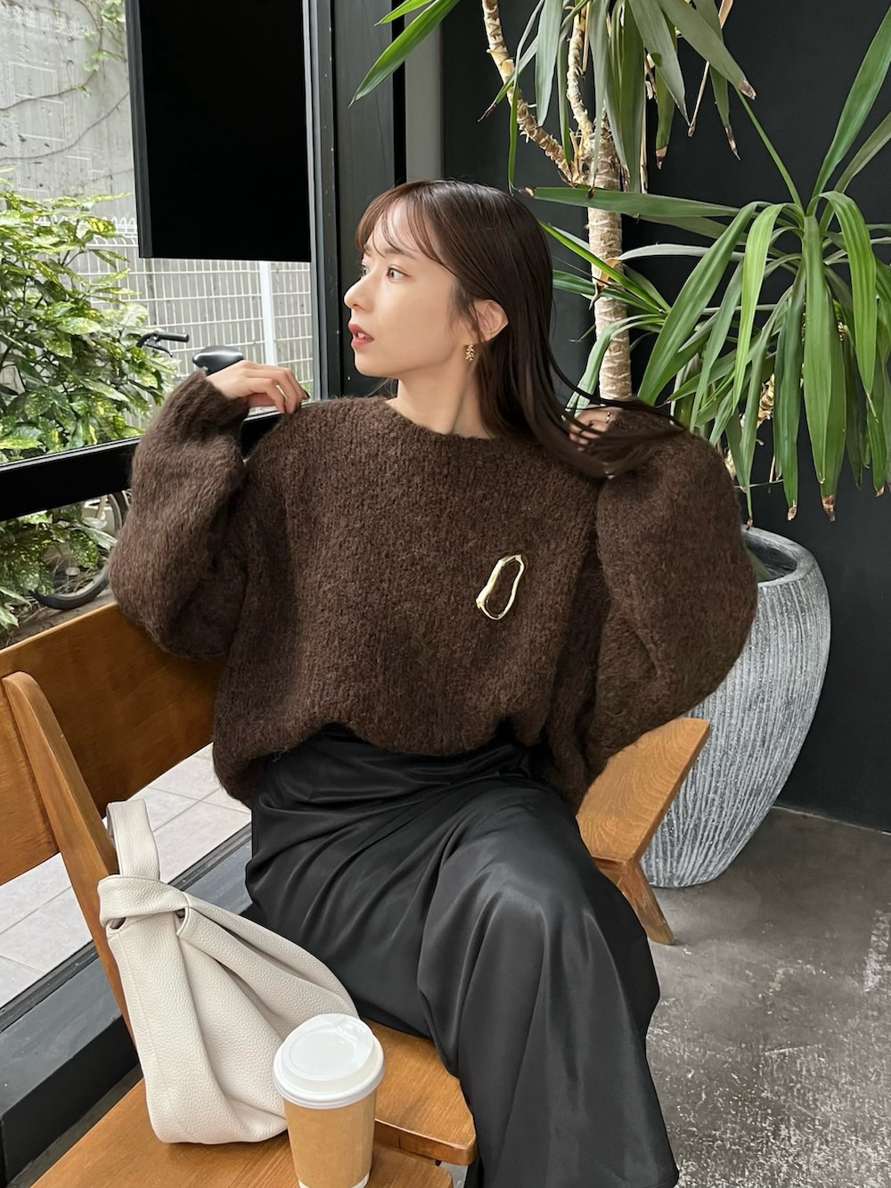 ブラック系のスカート、ブラウン系のニット/セーター、ホワイト系のハンドバッグを着用したレディースの秋コーディネートの2枚目の写真