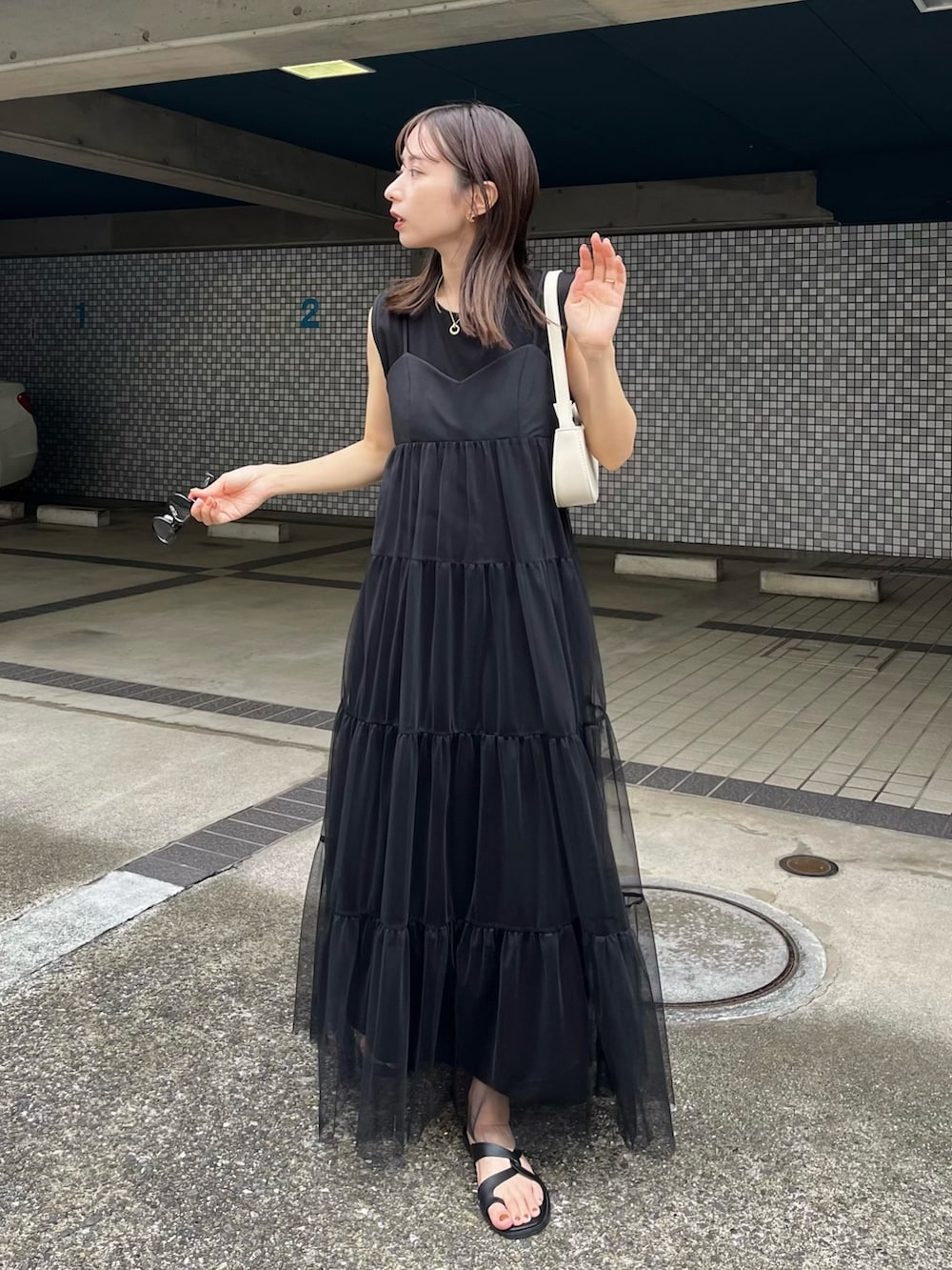 ブラック系のワンピース、ブラック系のその他シューズ、ホワイト系のショルダーバッグを着用したレディースの夏コーディネートの2枚目の写真