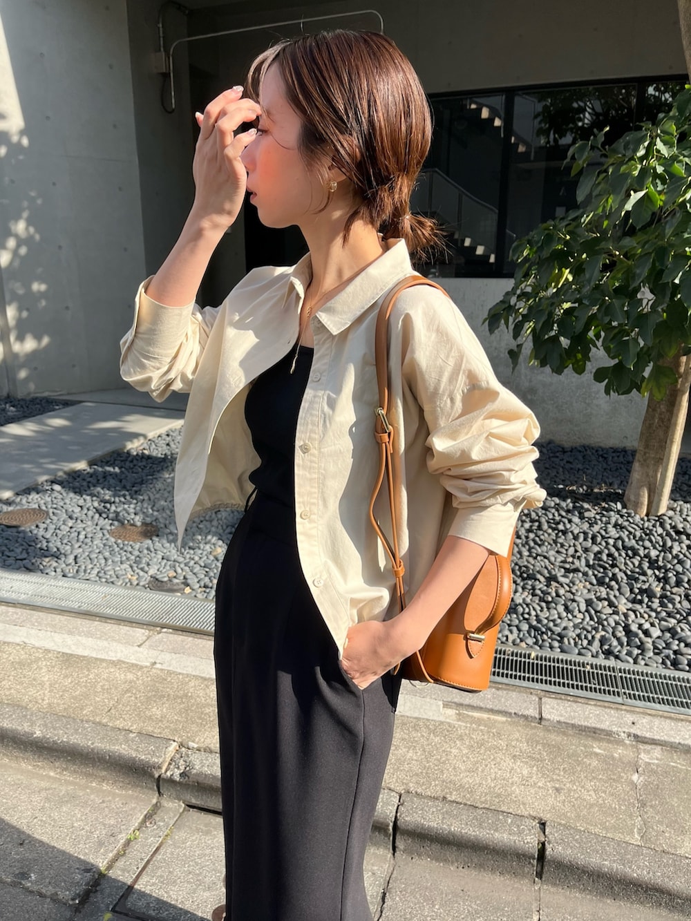 ブラック系のスカート、ベージュ系のショルダーバッグ、ブラック系のブーツを着用したレディースの春コーディネートの3枚目の写真