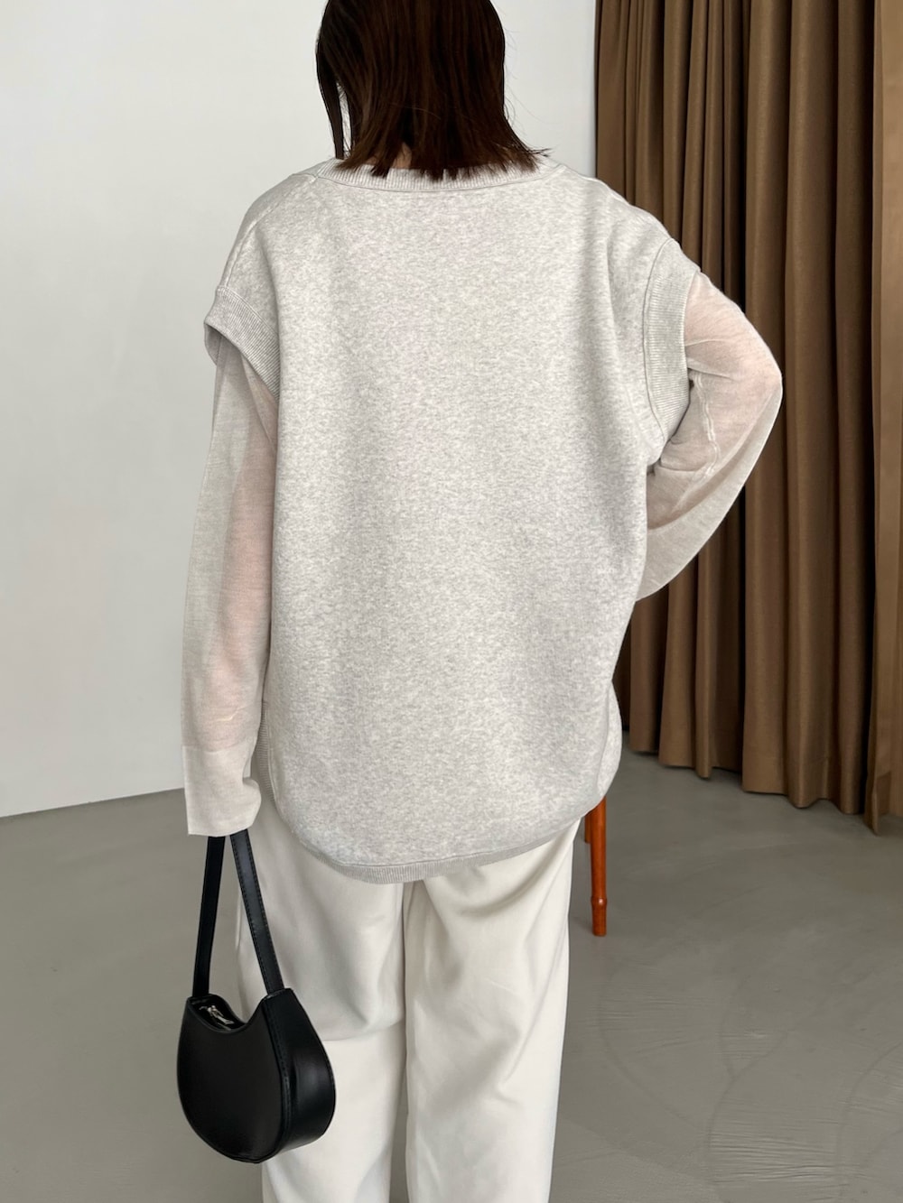 グレー系のベスト、ホワイト系のニット/セーター、ブラック系のパンプスを着用したレディースの秋コーディネートの4枚目の写真