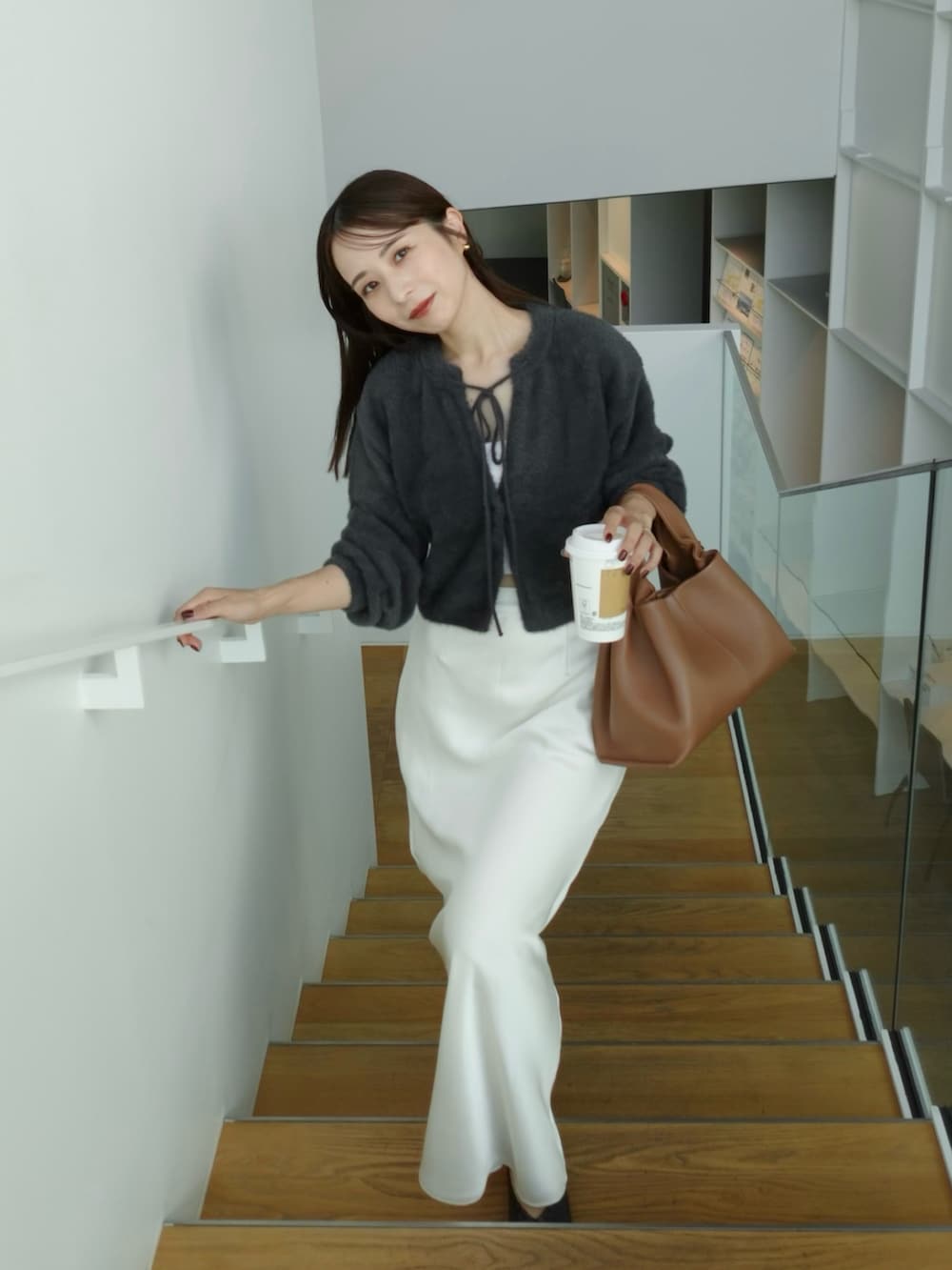 ホワイト系のスカート、ブラウン系のバッグ、グレー系のカーディガン/ボレロを着用したレディースの秋コーディネートの2枚目の写真