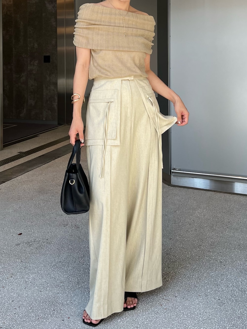 ベージュ系のその他パンツ、ベージュ系のニット/セーター、ブラック系のショルダーバッグを着用したレディースの夏コーディネートの2枚目の写真