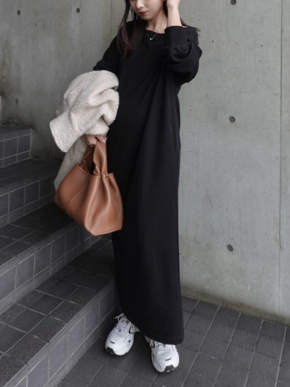 ブラック系のワンピース、ホワイト系のスニーカー、ブラウン系のバッグを着用したレディースの冬コーディネートの2枚目の写真