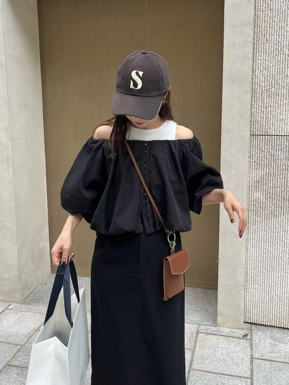 ブラック系のスカート、ブラック系のシャツ/ブラウス、ブラウン系のショルダーバッグを着用したレディースの秋コーディネートの2枚目の写真